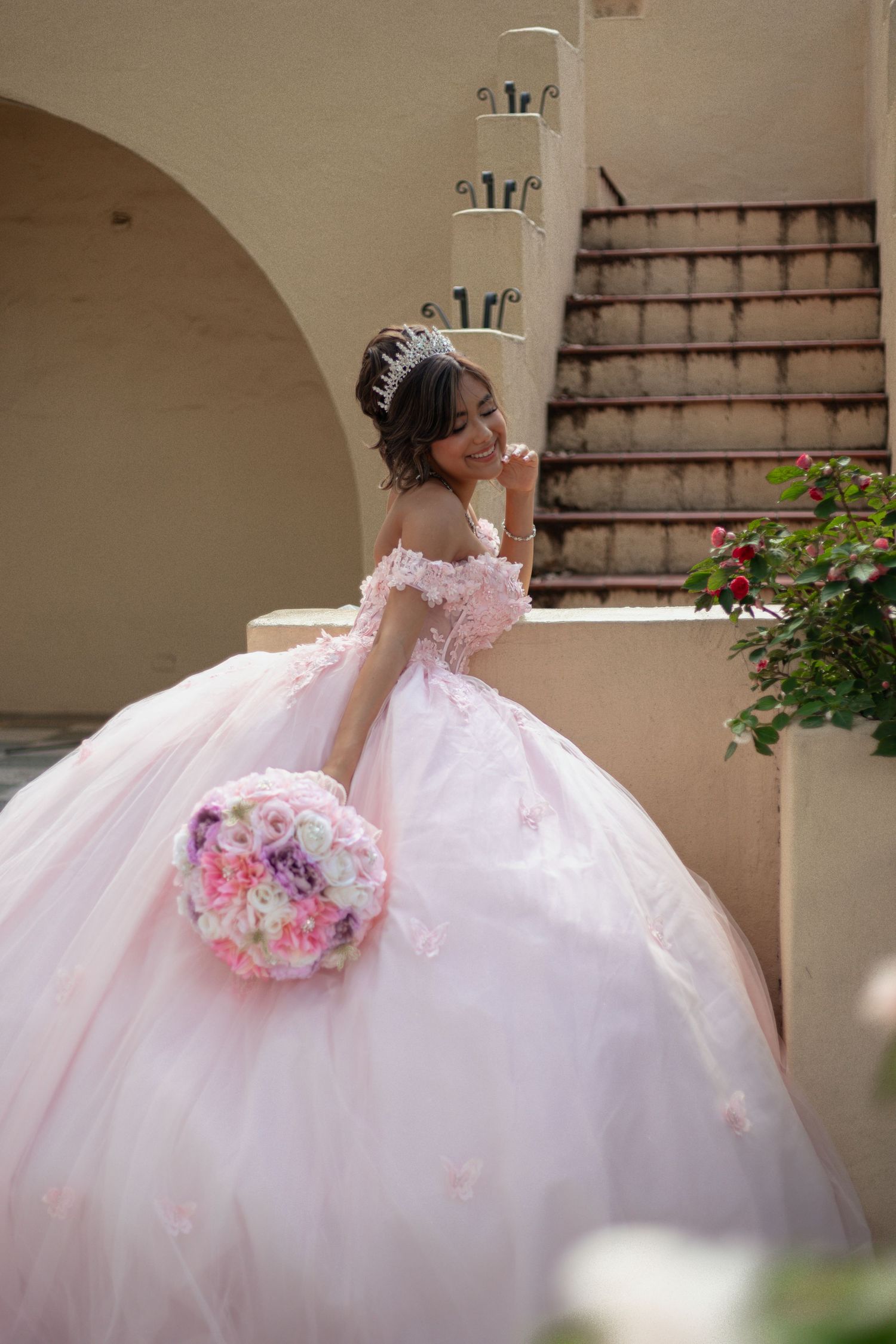 Dramatic ballgown silhouette against stone columns with pink floral details.