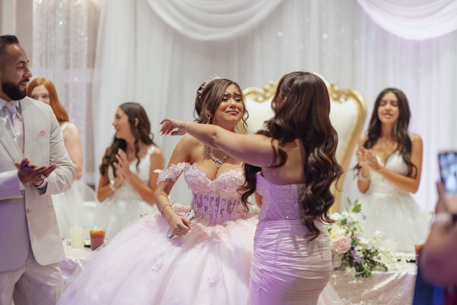 Wedding reception celebration with guests dancing in purple and white decorated venue.