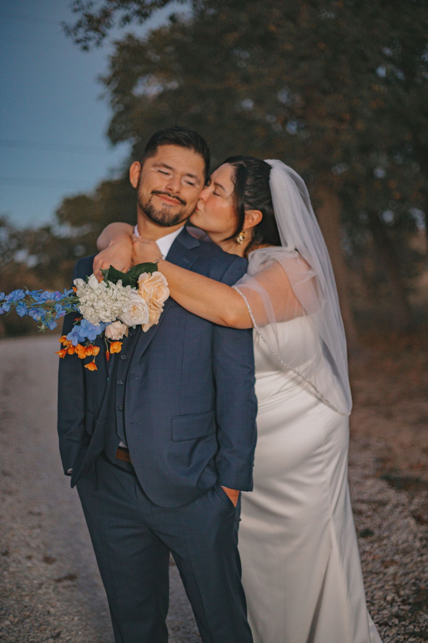 Couple embraces during intimate outdoor wedding photo session at dusk.