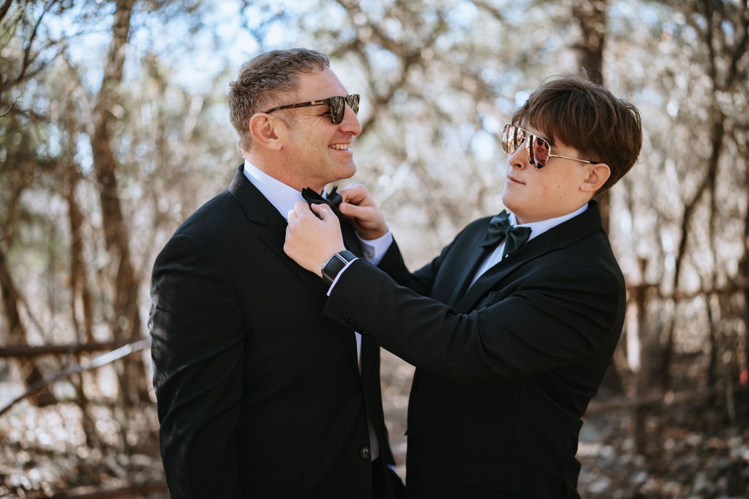 Two people in formal attire sharing an intimate embrace outdoors.