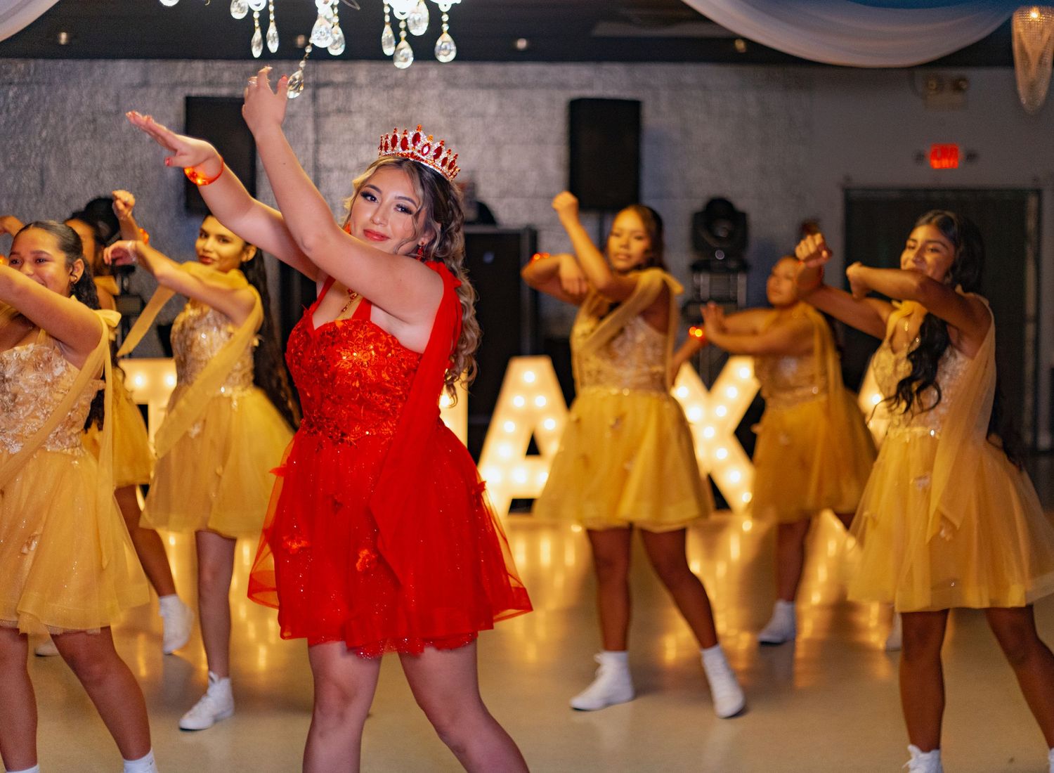 Dancers in red and yellow dresses perform a choreographed routine at a celebration.