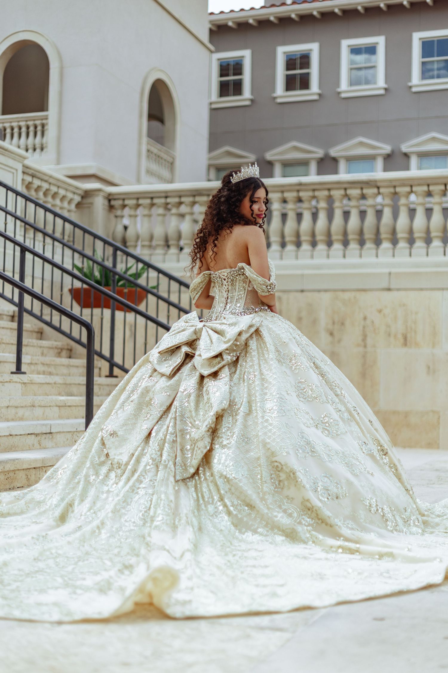 An ornate white wedding gown with a dramatic train flows down elegant stone steps.