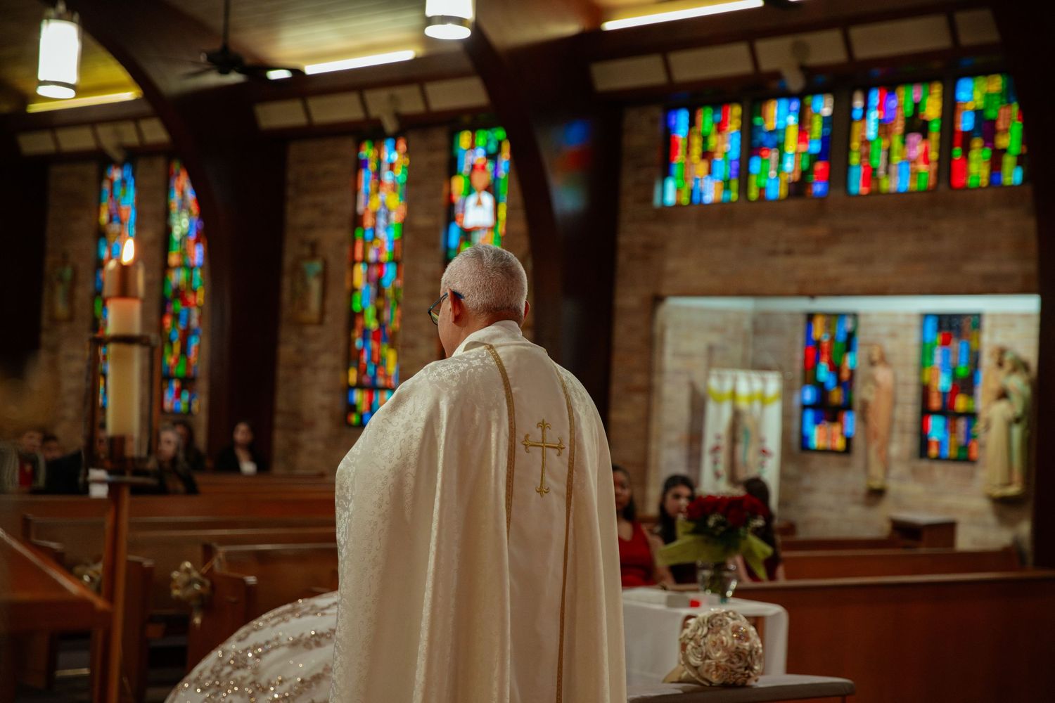 Church interior with colorful stained glass windows and white ceremonial attire.