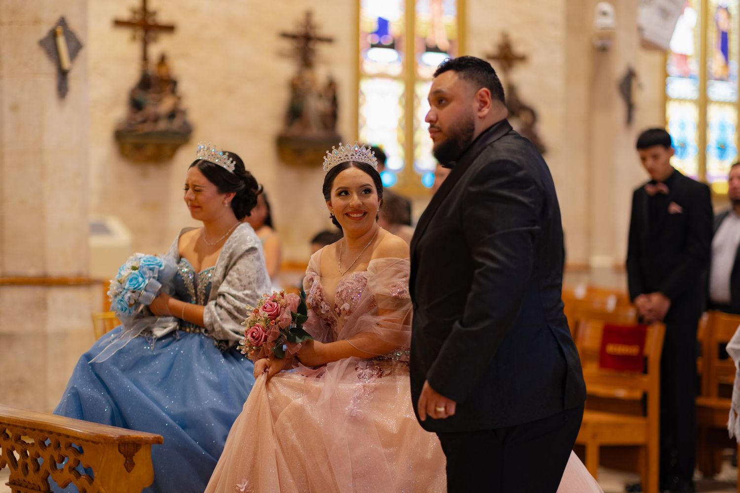 Formal celebration in church with attendees wearing elegant gowns and formal attire.