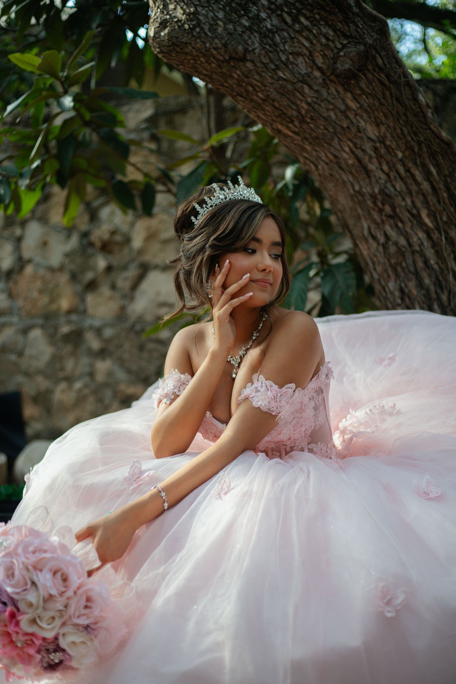 Artistic portrait in a flowing pink gown under a tree canopy.