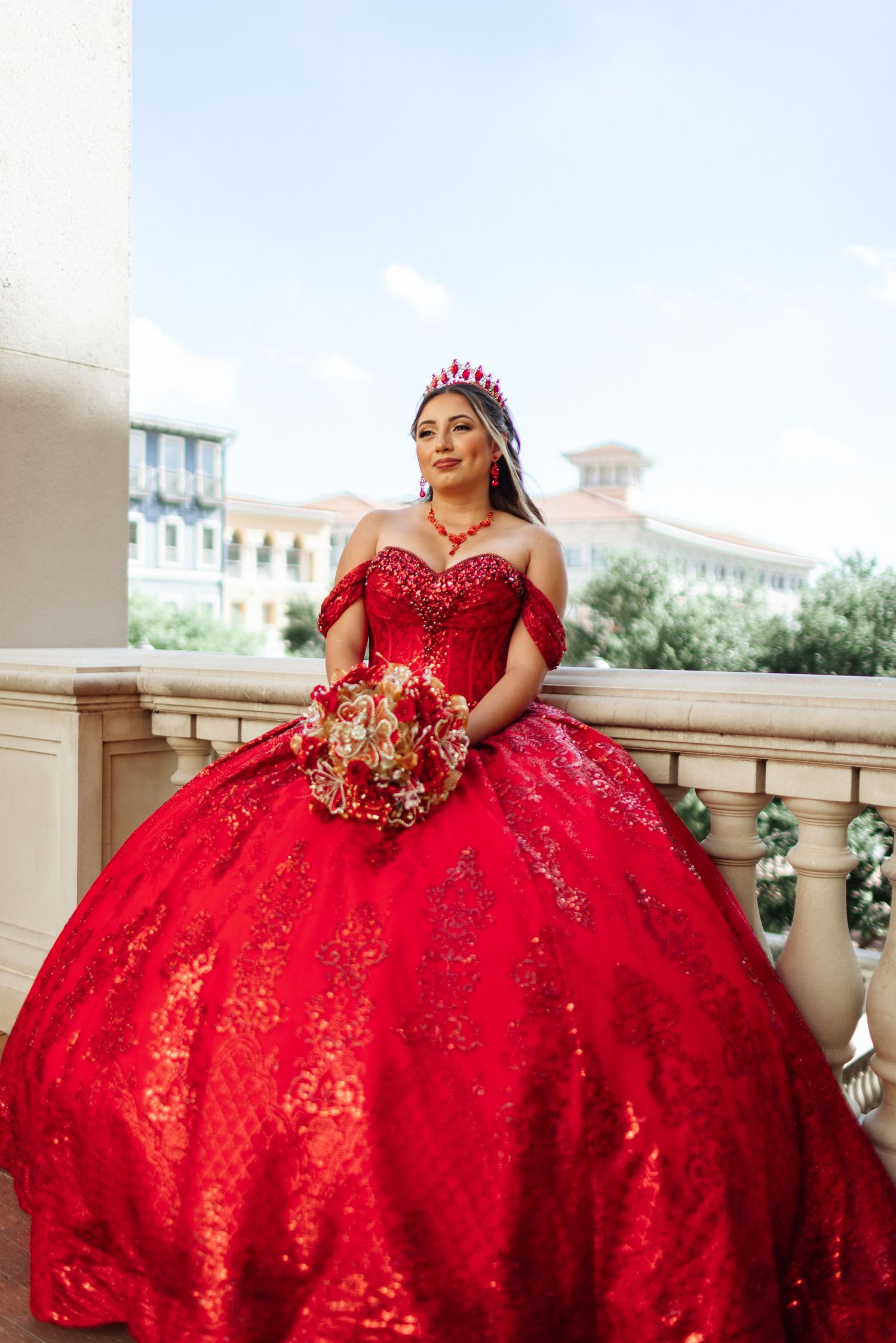 Stunning red ballgown with sequins and beading photographed in an elegant outdoor setting.