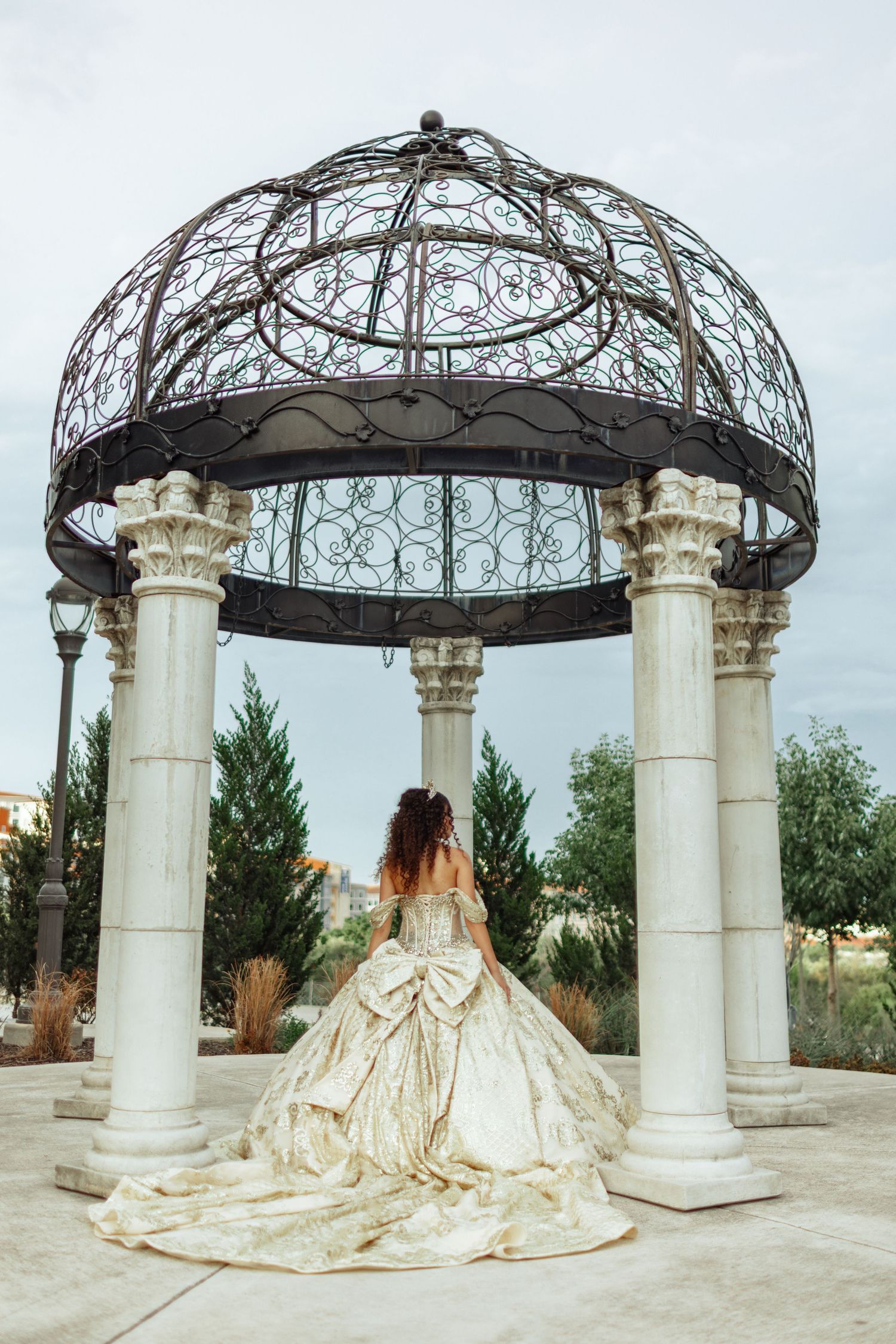 A grand outdoor gazebo with ornate metal dome and white columns surrounded by flowing white fabric.