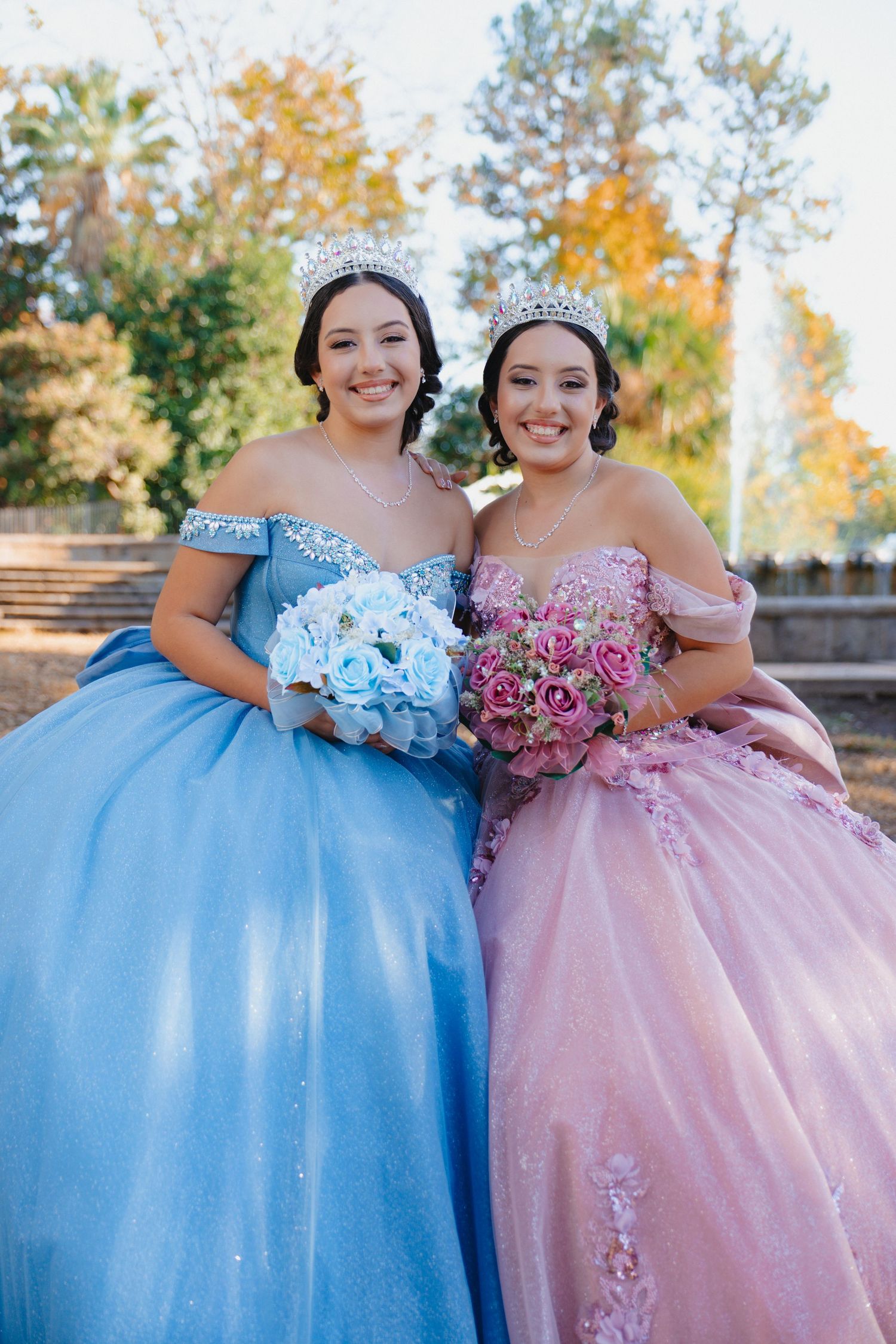 Festive outdoor portrait of matching ballgowns in powder blue and blush pink.