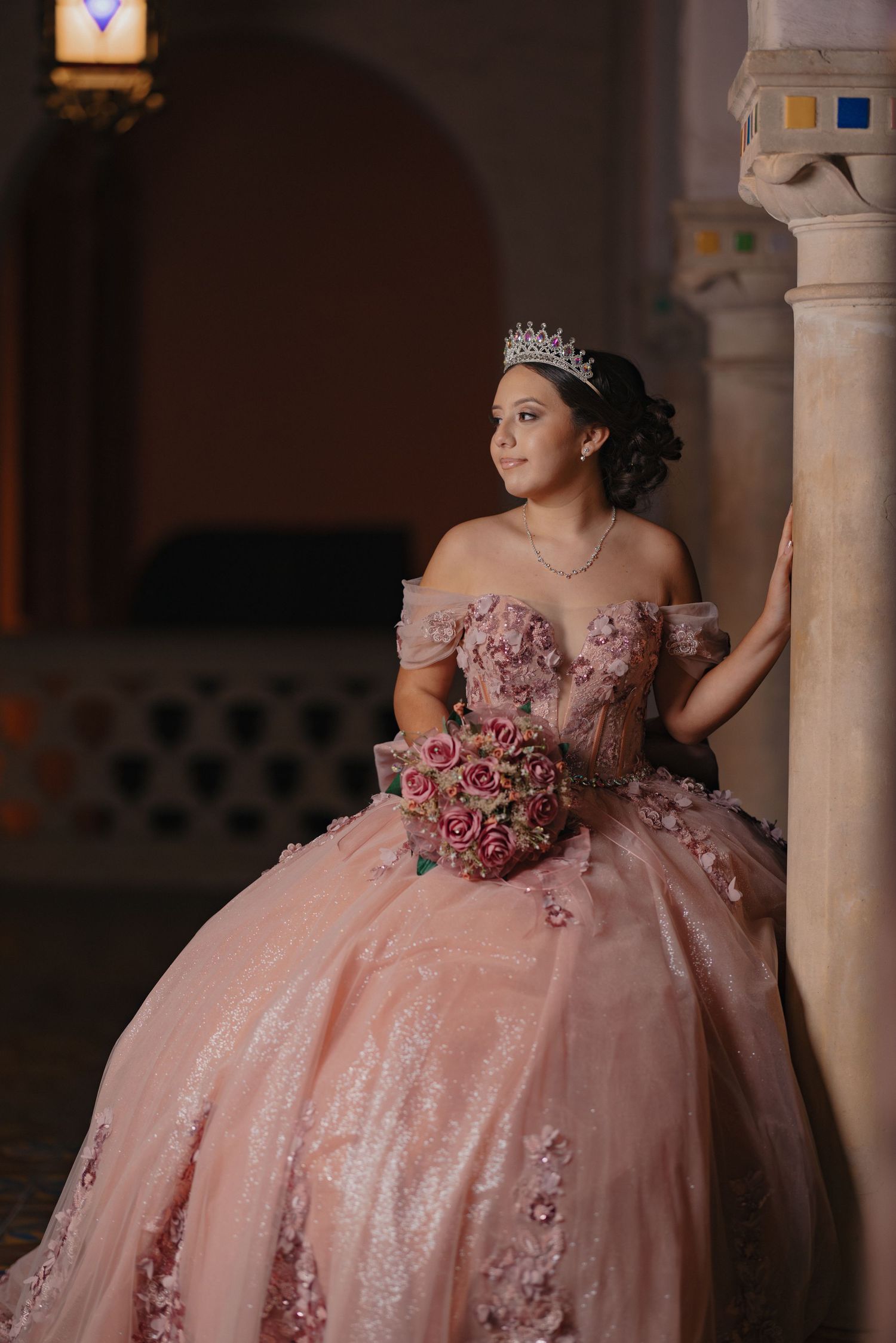 Pink ball gown with floral details photographed in an elegant columned setting.