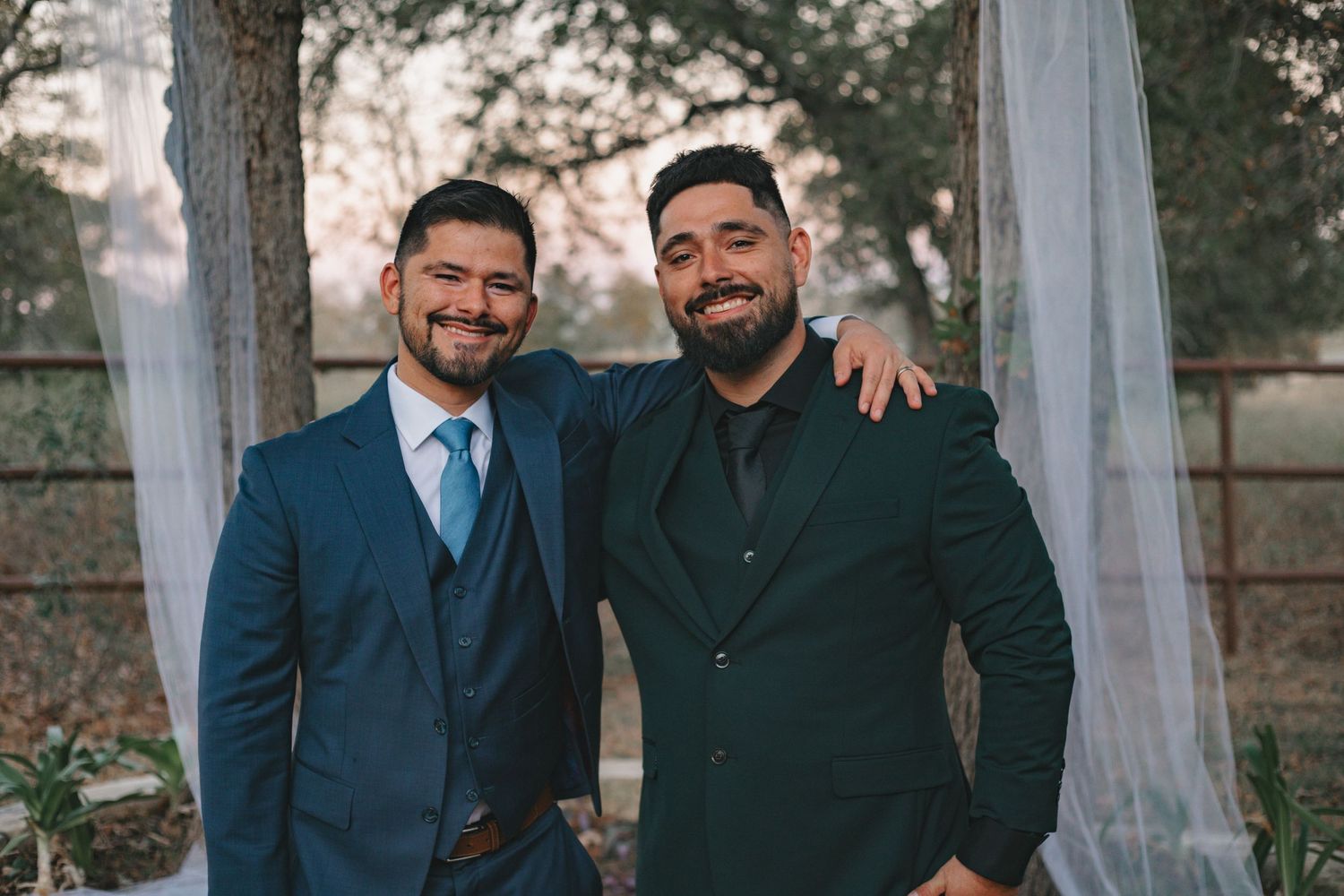 Wedding party members in navy suits and formal attire pose together outdoors.