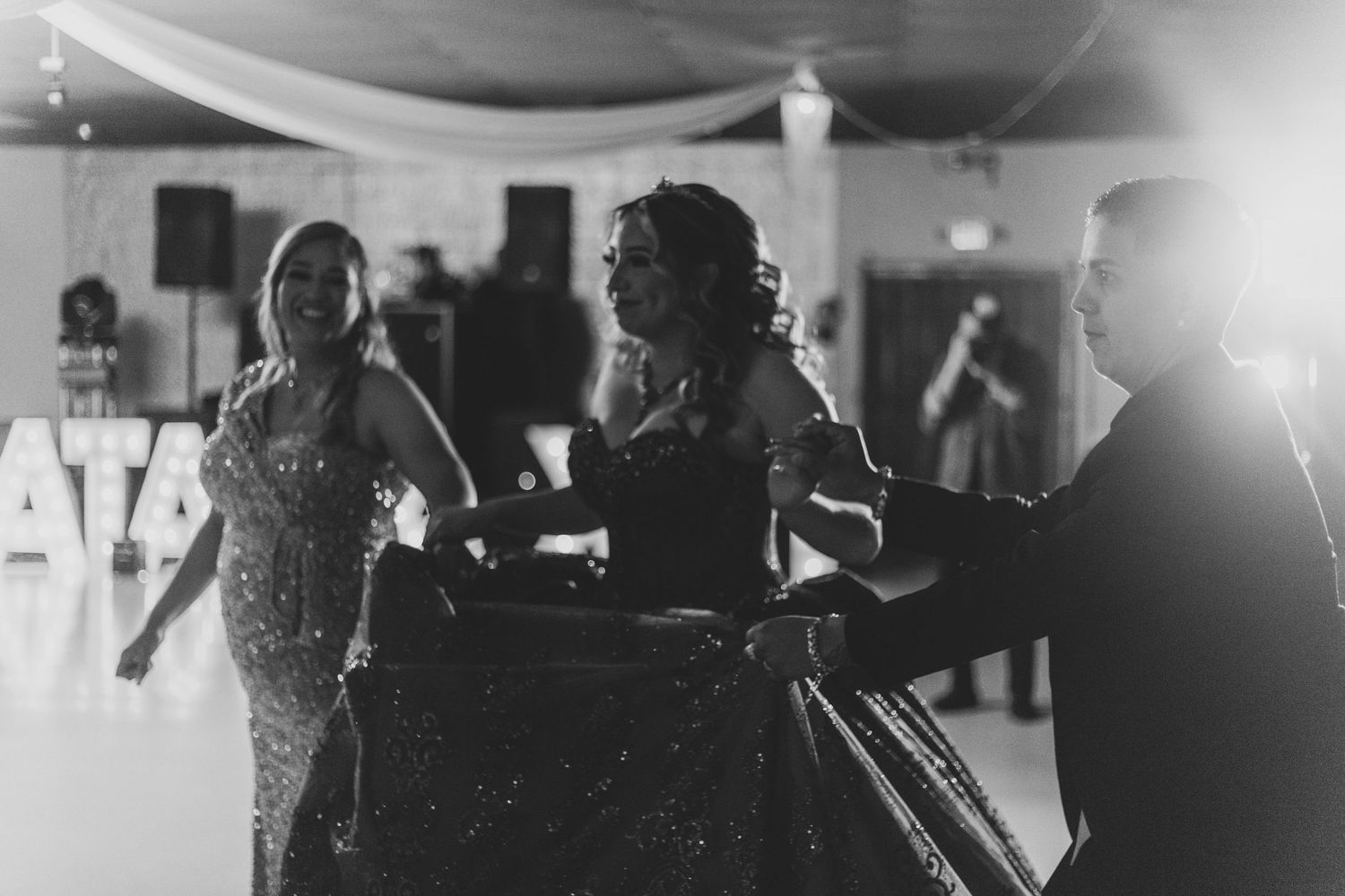Black and white candid shot of a formal celebration with decorative lighting.