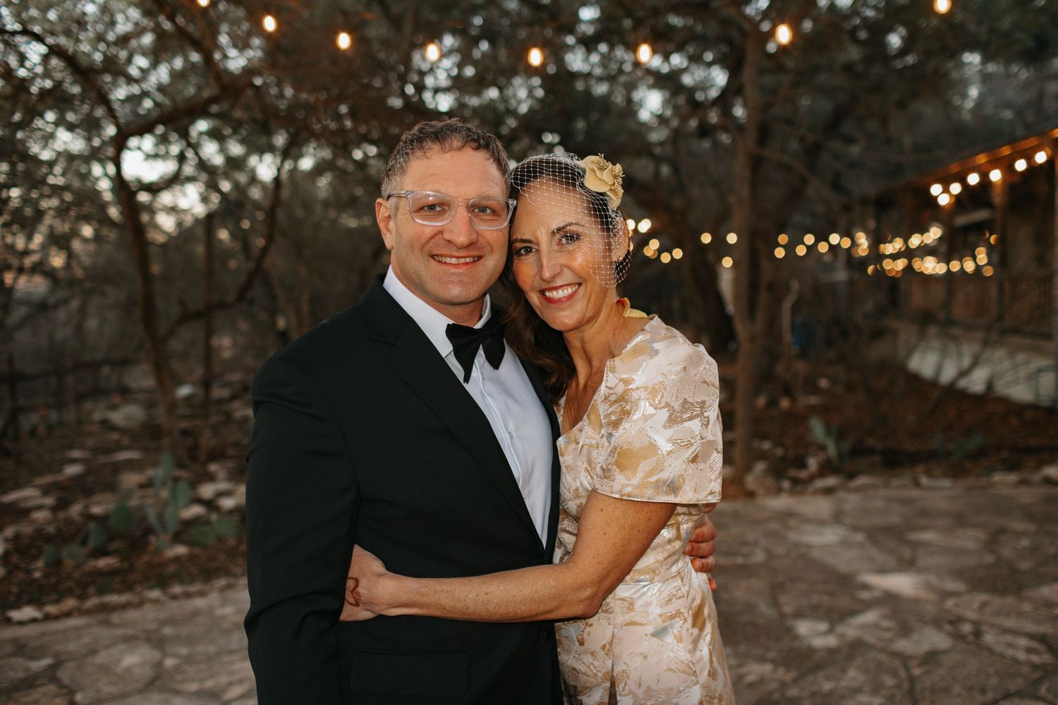 Romantic outdoor wedding portraits with string lights and natural scenery.