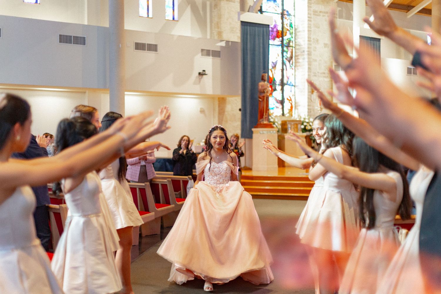 Group of bridesmaids in light pink dresses dancing together in church.