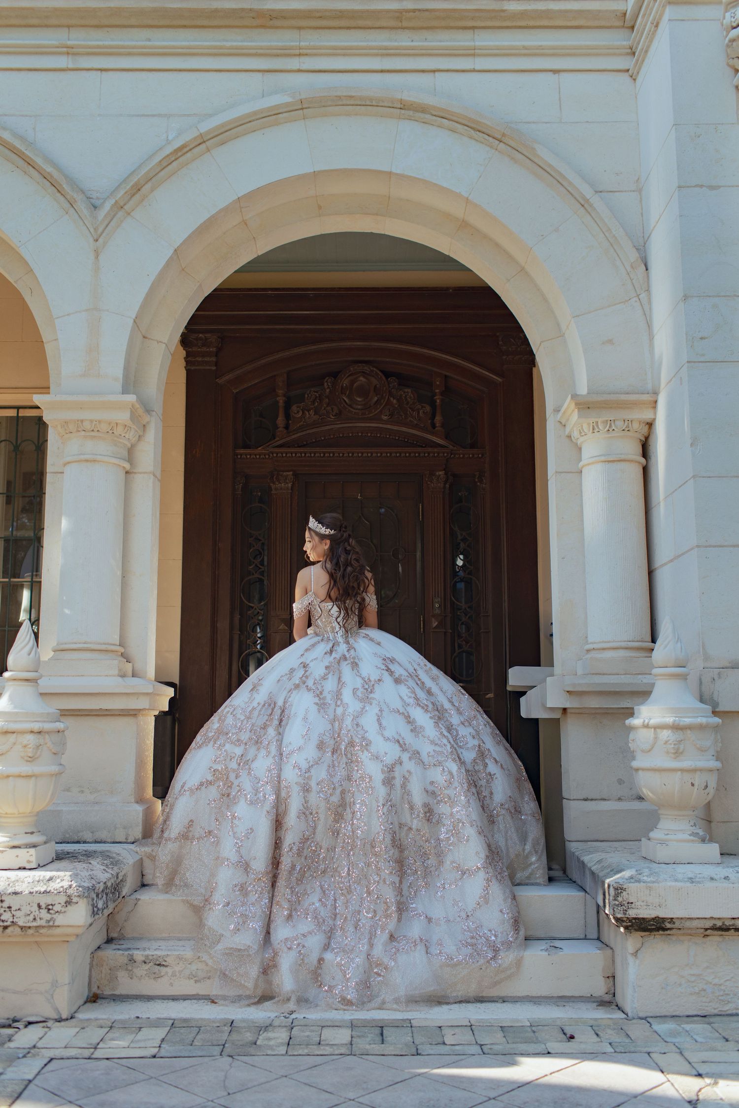 Elegant ballgown wedding dress with intricate details photographed in front of classic architectural archway.