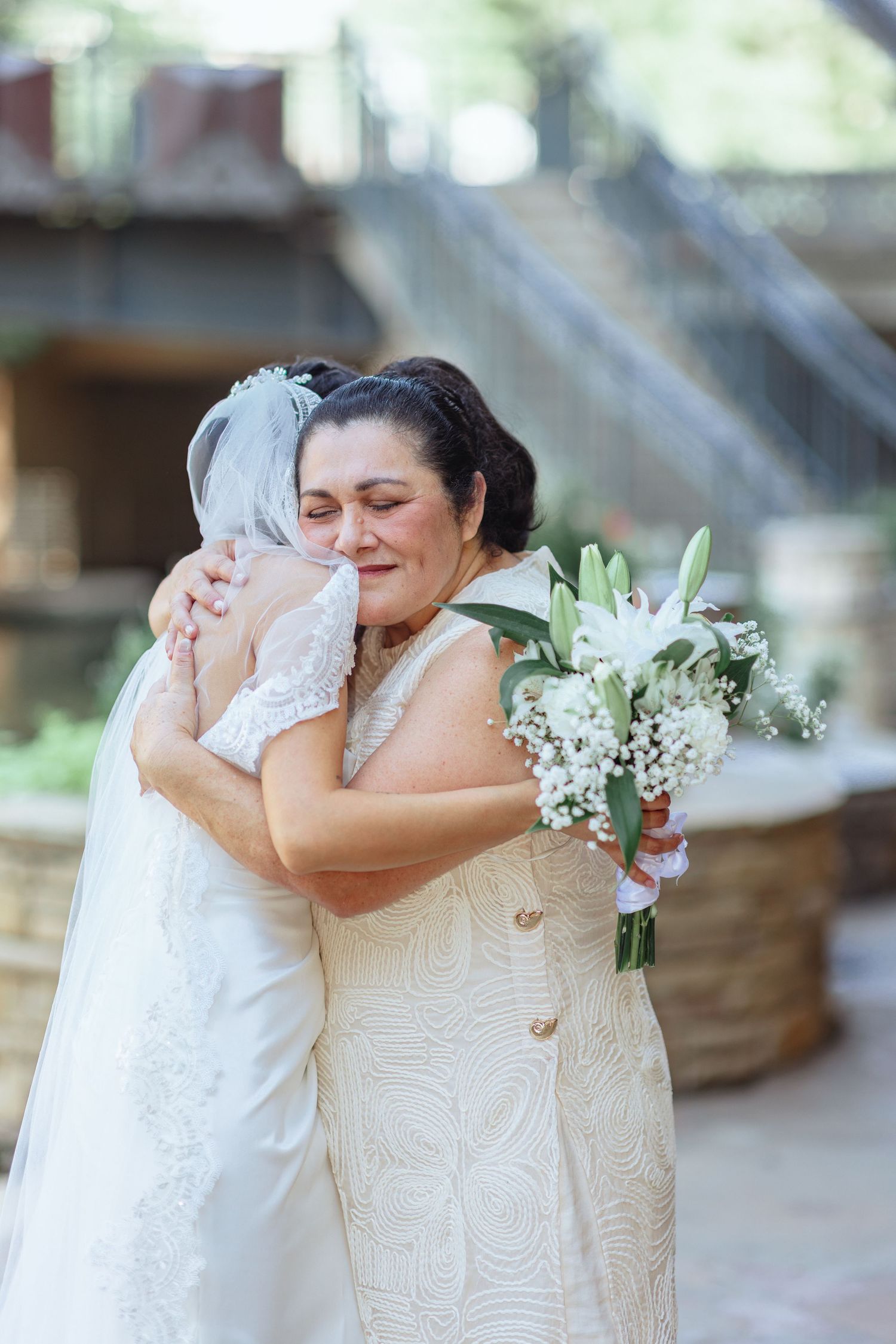 Two people in wedding attire share tearful embraces during an emotional moment.