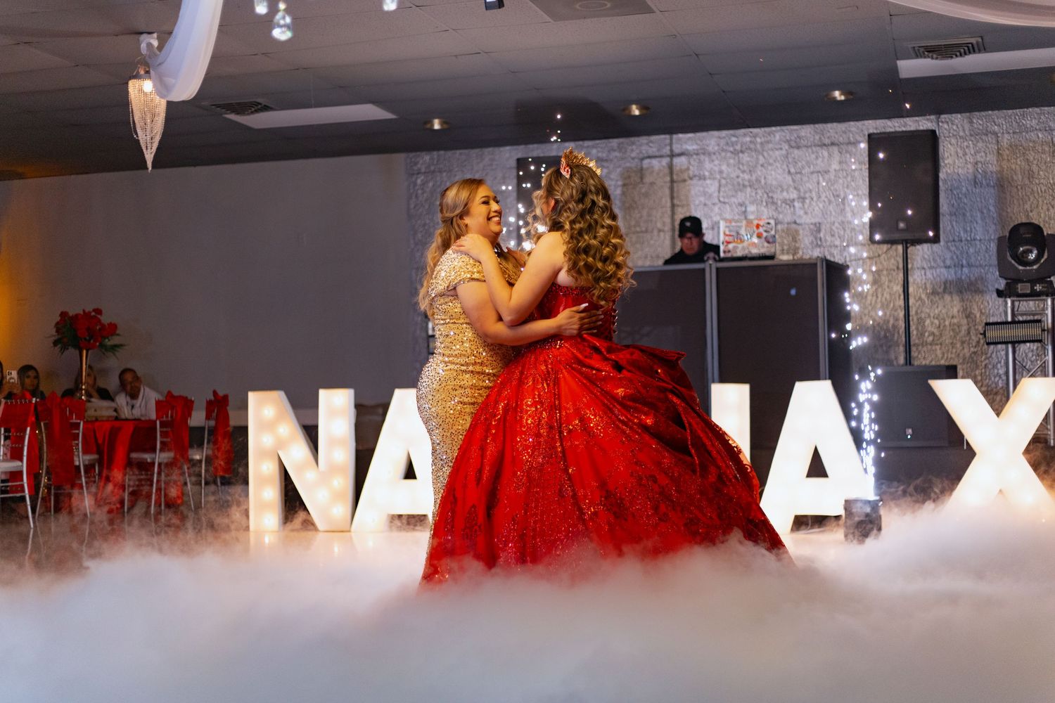 A red ballgown sparkles through atmospheric fog during a special celebration dance.