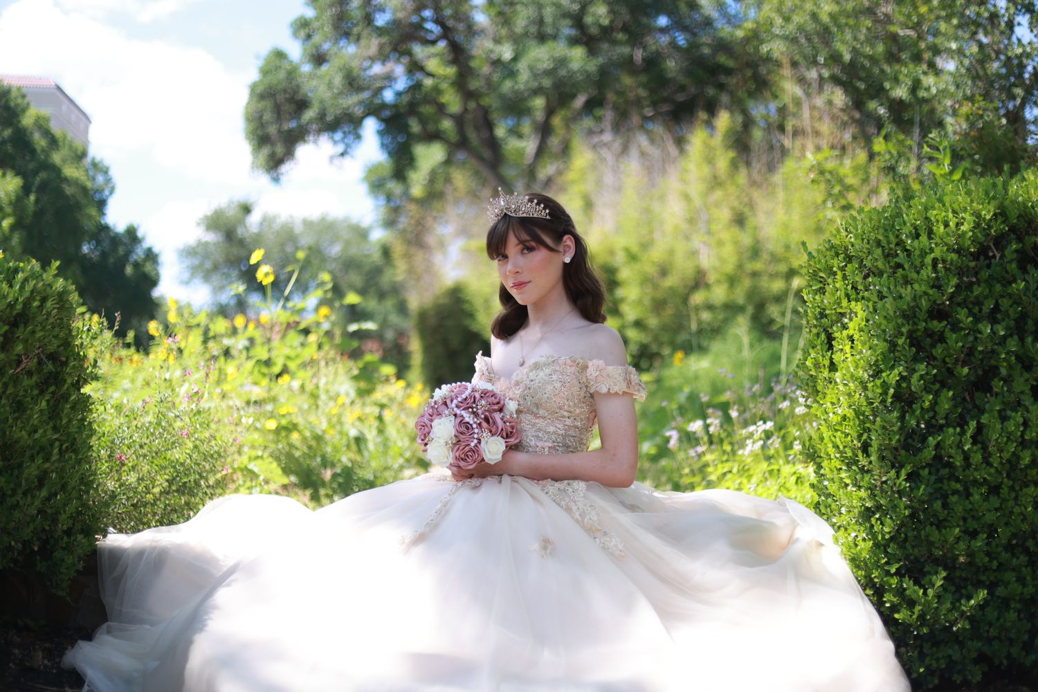 Flowing white ballgown dress photographed in an outdoor garden setting.