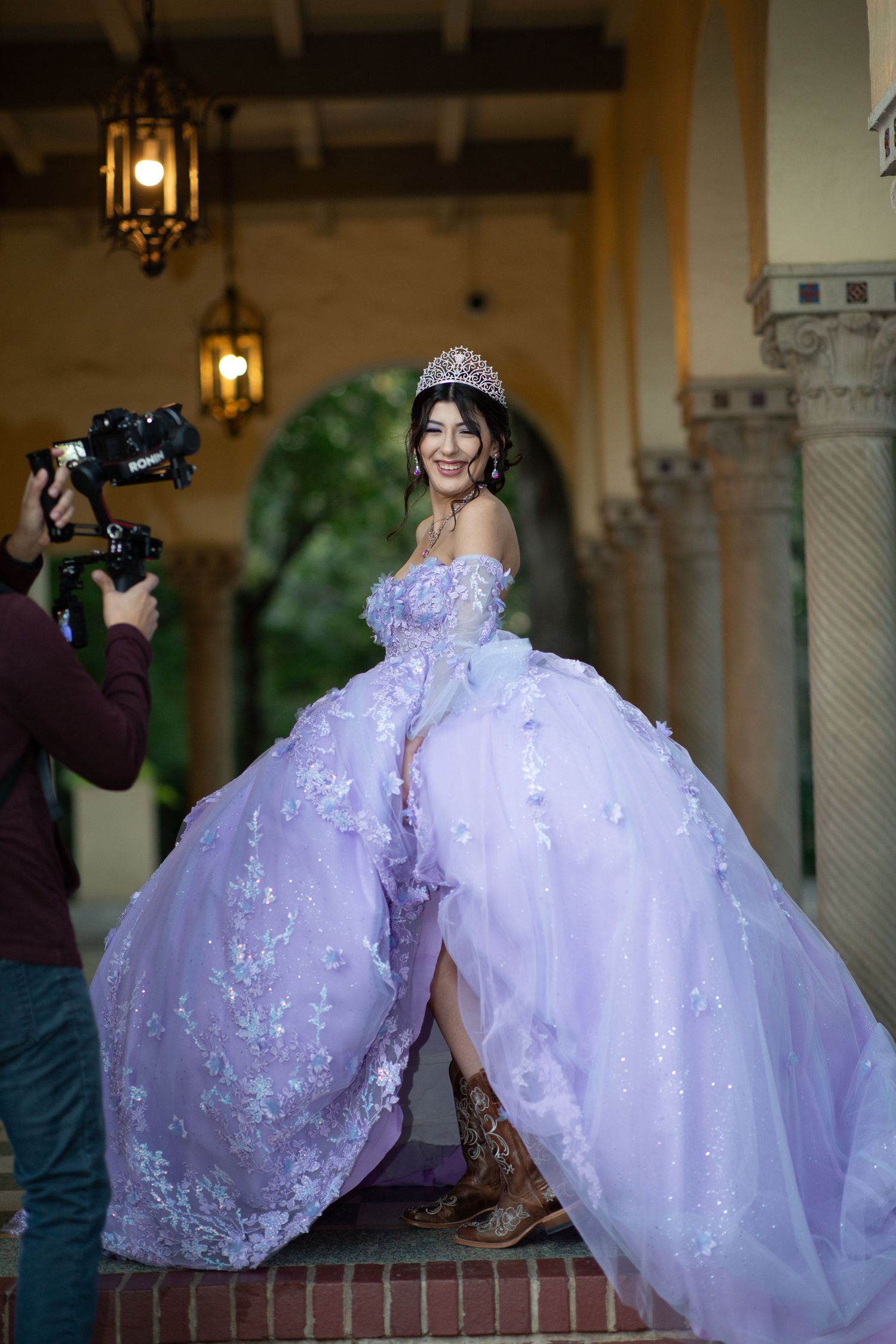 A lavender princess gown with intricate embroidery photographed in an elegant courtyard setting.