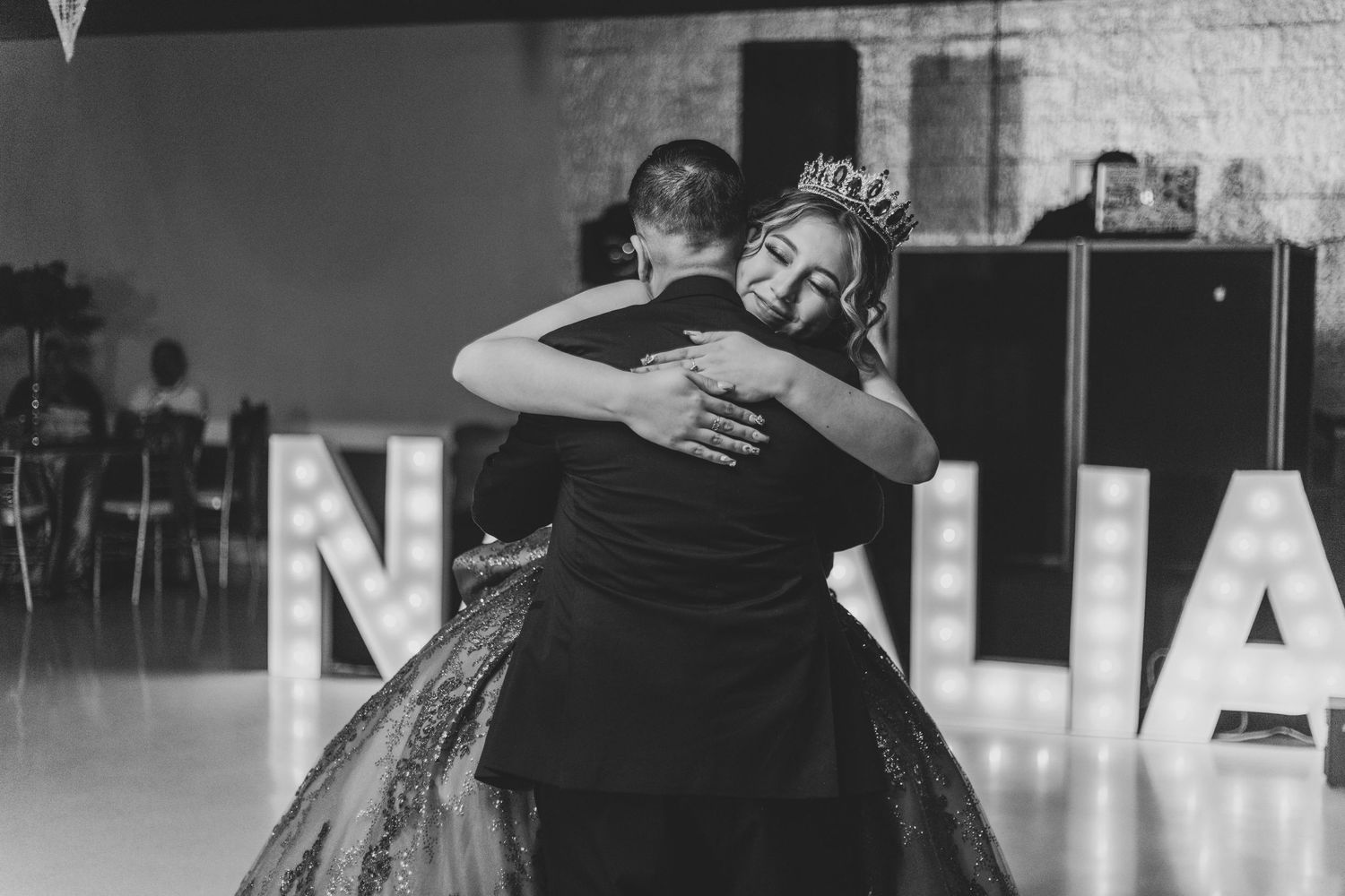 Black and white photo of an emotional embrace during a formal celebration.
