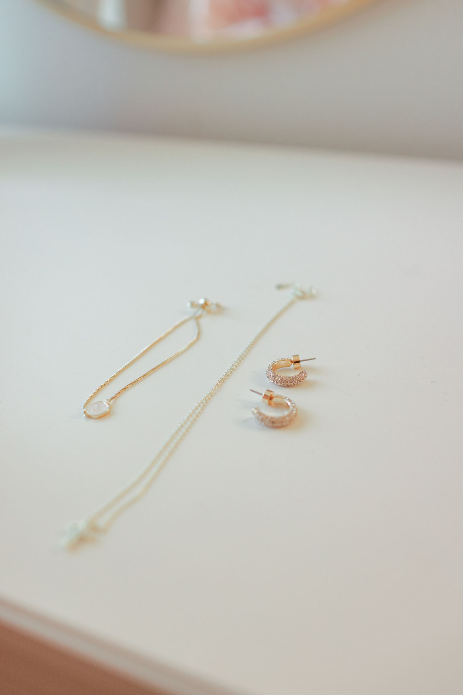 Delicate gold jewelry pieces arranged on white surface in soft focus.