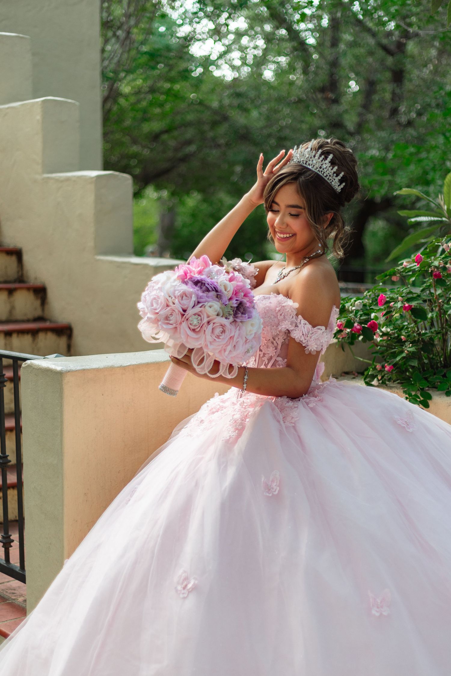 Romantic pose in a voluminous pink and white ballgown with floral accents.