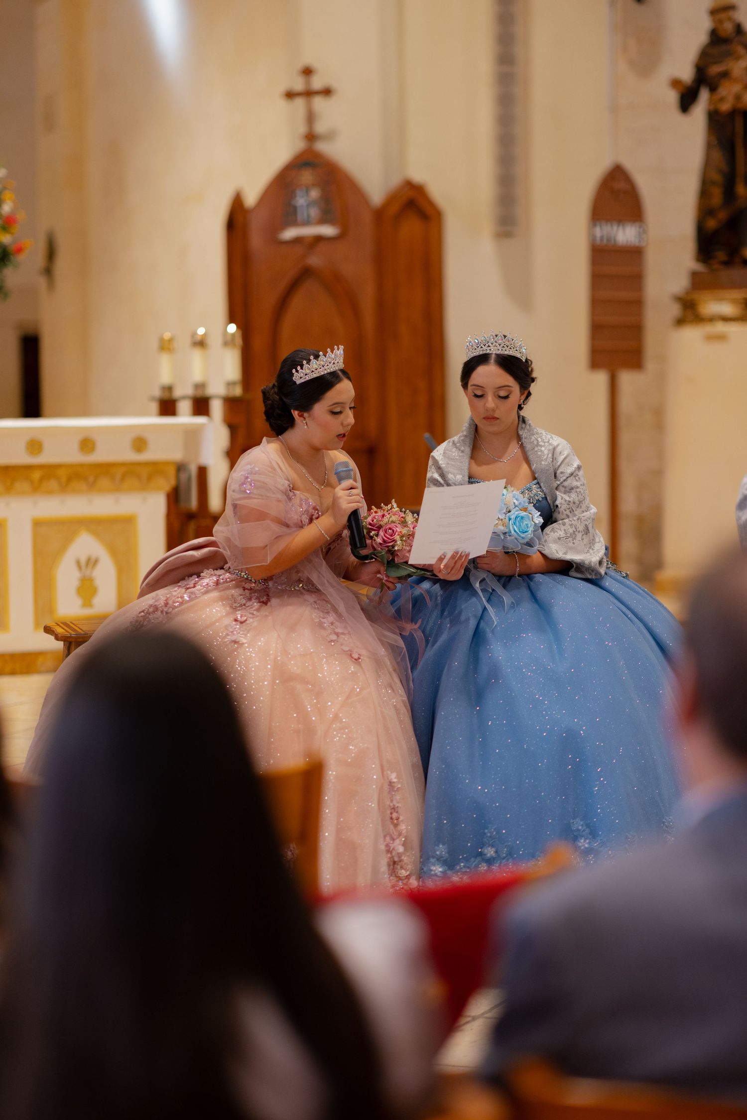 Two elegant ballgowns in pink and blue during a church ceremony.