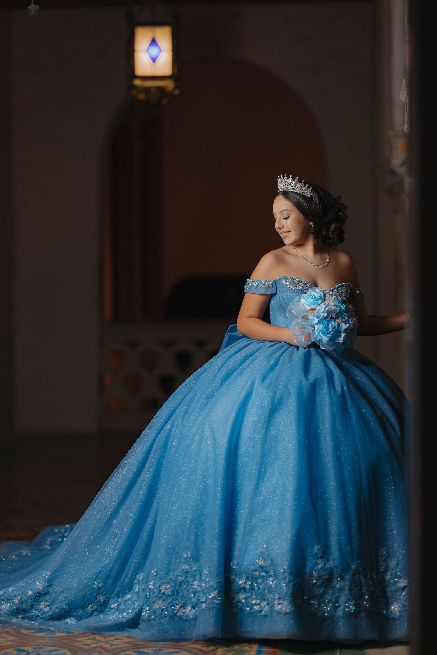 Royal blue ball gown with crystal details photographed in dramatic low light setting.