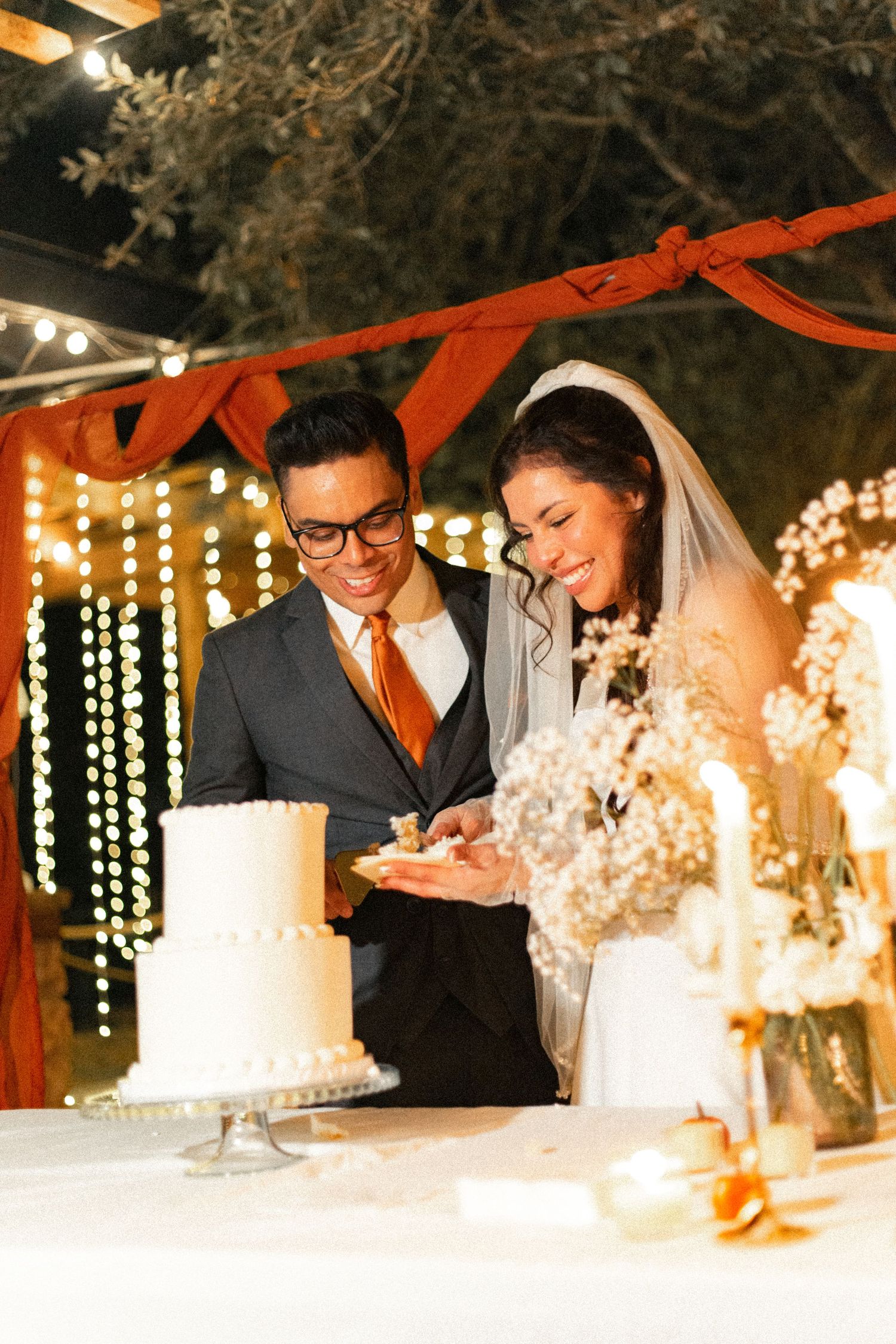 Wedding couple leaning over their white cake during the traditional cake cutting ceremony.