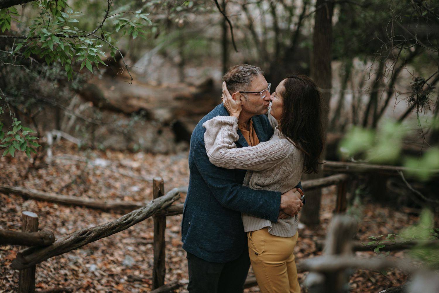 Couple embracing in romantic outdoor forest engagement photoshoot.