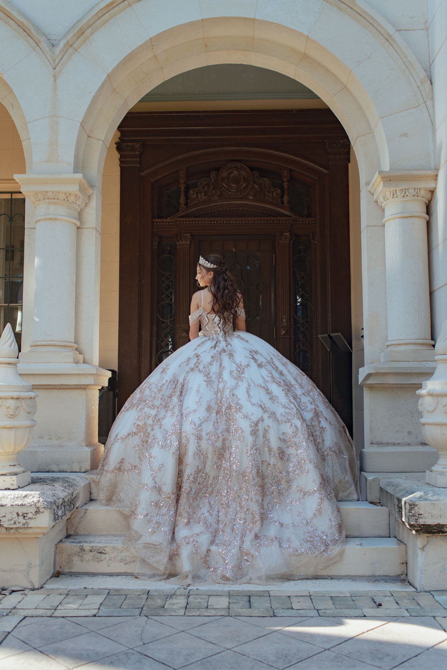 Elegant white and gold ballgown photographed under classic archways.