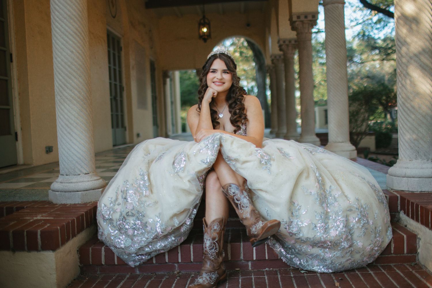 A stunning bridal portrait featuring an ornate white lace gown against a backdrop of classic columns.
