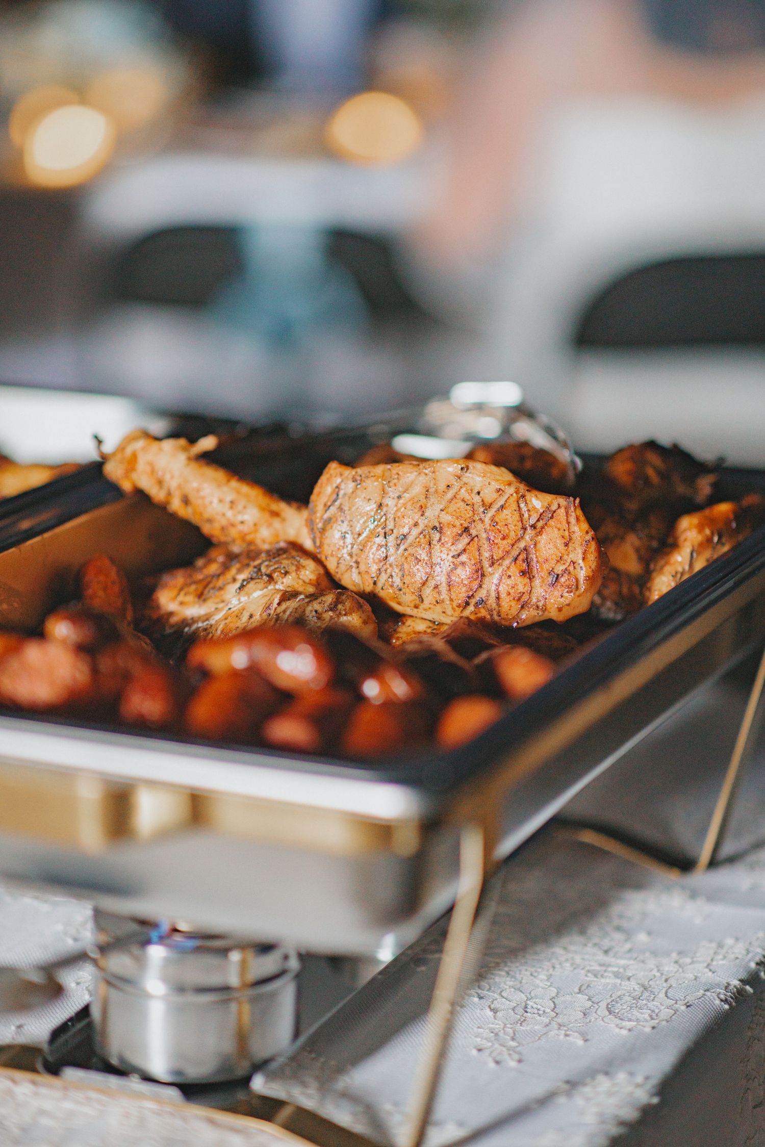 Grilled meats and vegetables cooking on stainless steel warming trays.