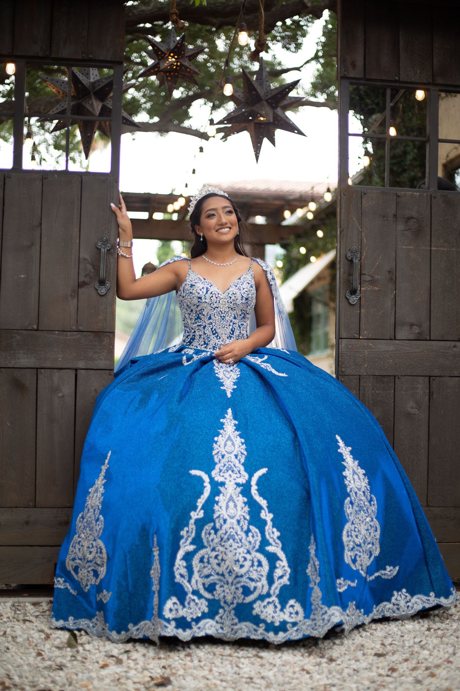 Beautiful blue ball gown with white embellishments photographed in outdoor garden setting.