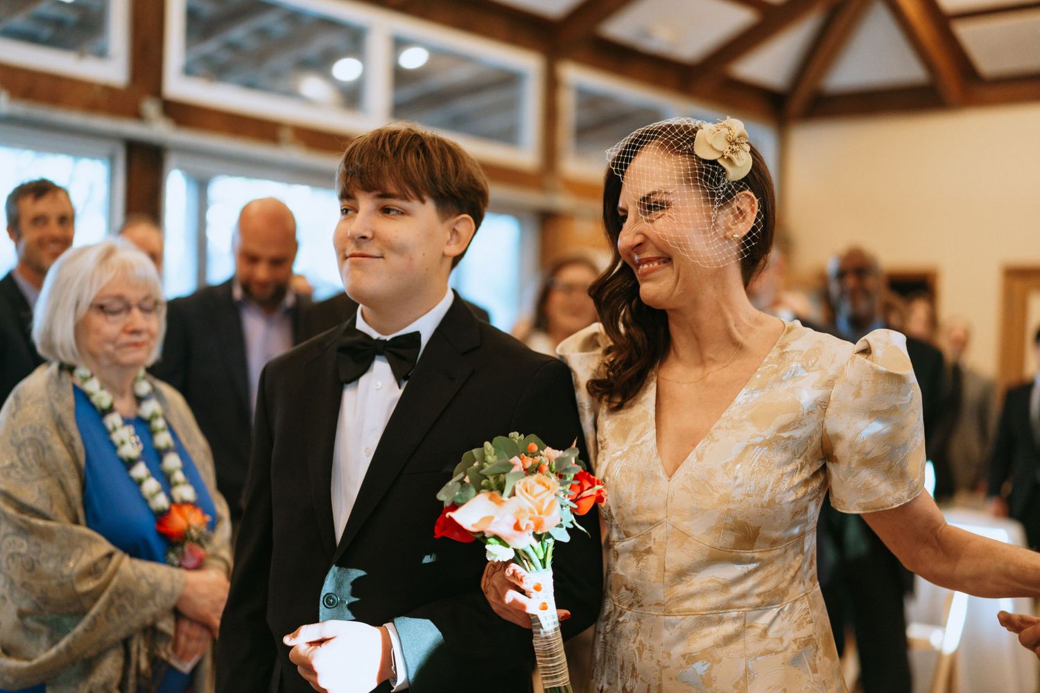 Wedding reception scene in rustic wooden venue with guests gathered at tables.