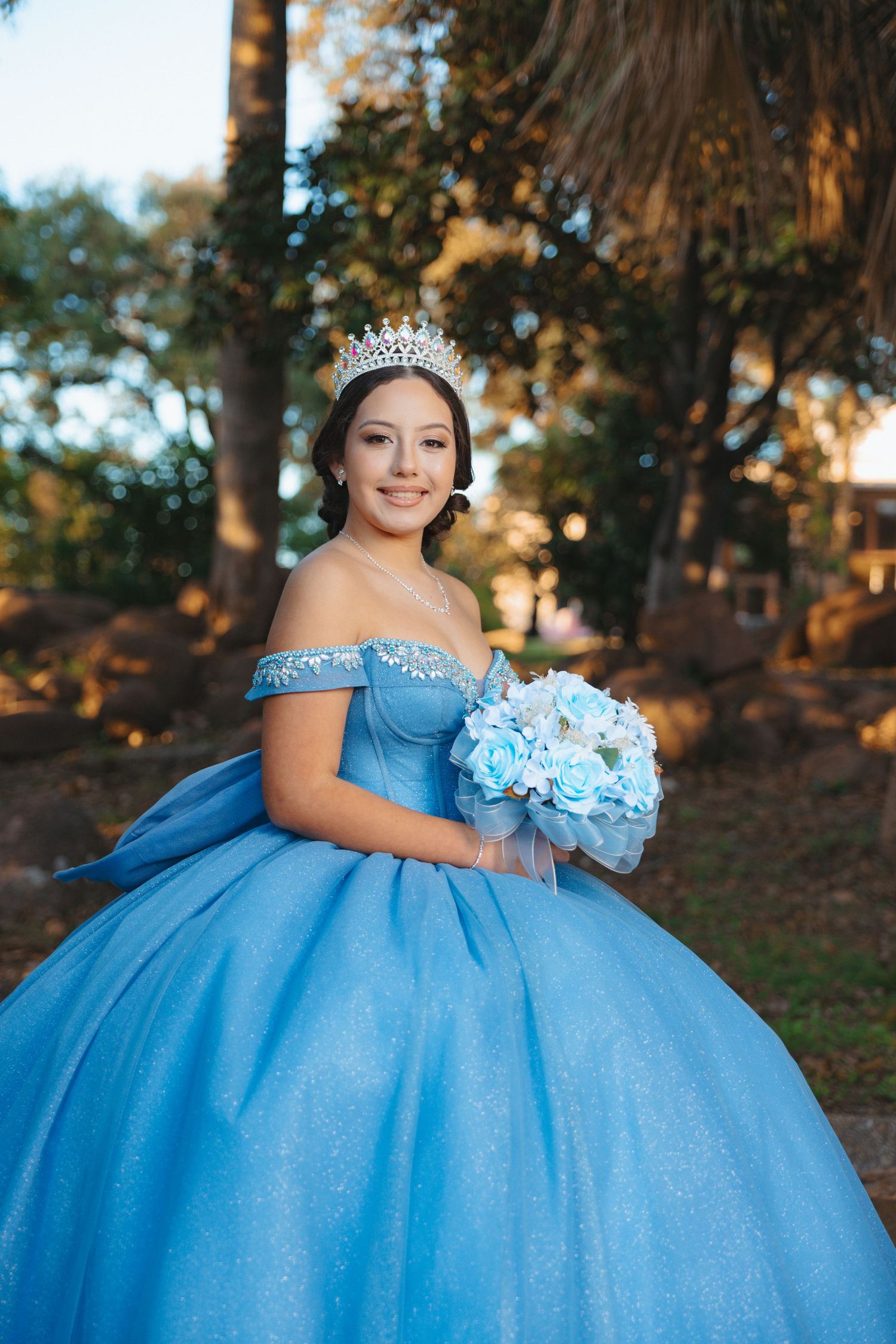 Light blue princess ball gown with matching bouquet photographed in a natural outdoor setting.