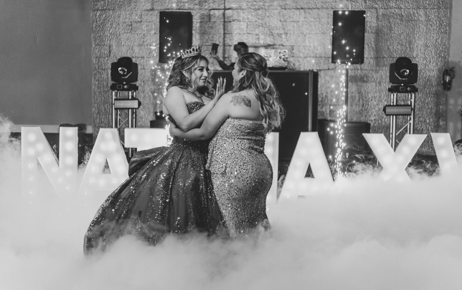 Black and white photo of a dance moment with illuminated letters in the background.