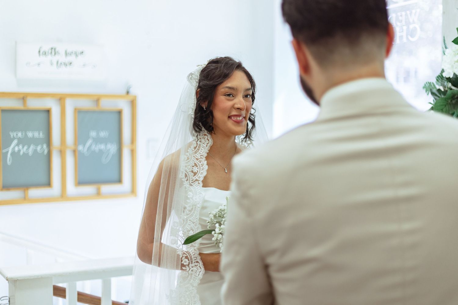 An intimate wedding ceremony moment in a light-filled room with greenery.