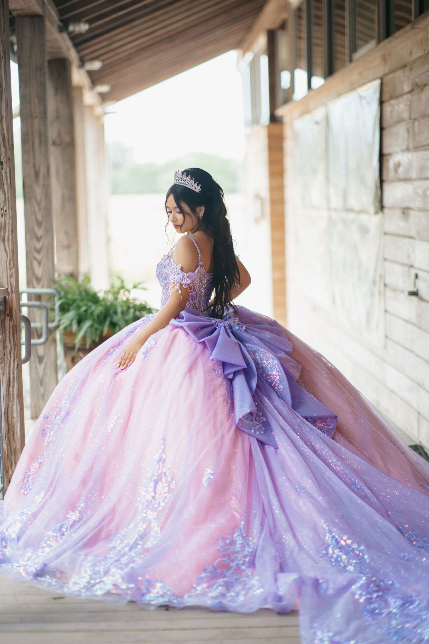 A flowing lavender ball gown with dramatic train photographed on a covered porch.