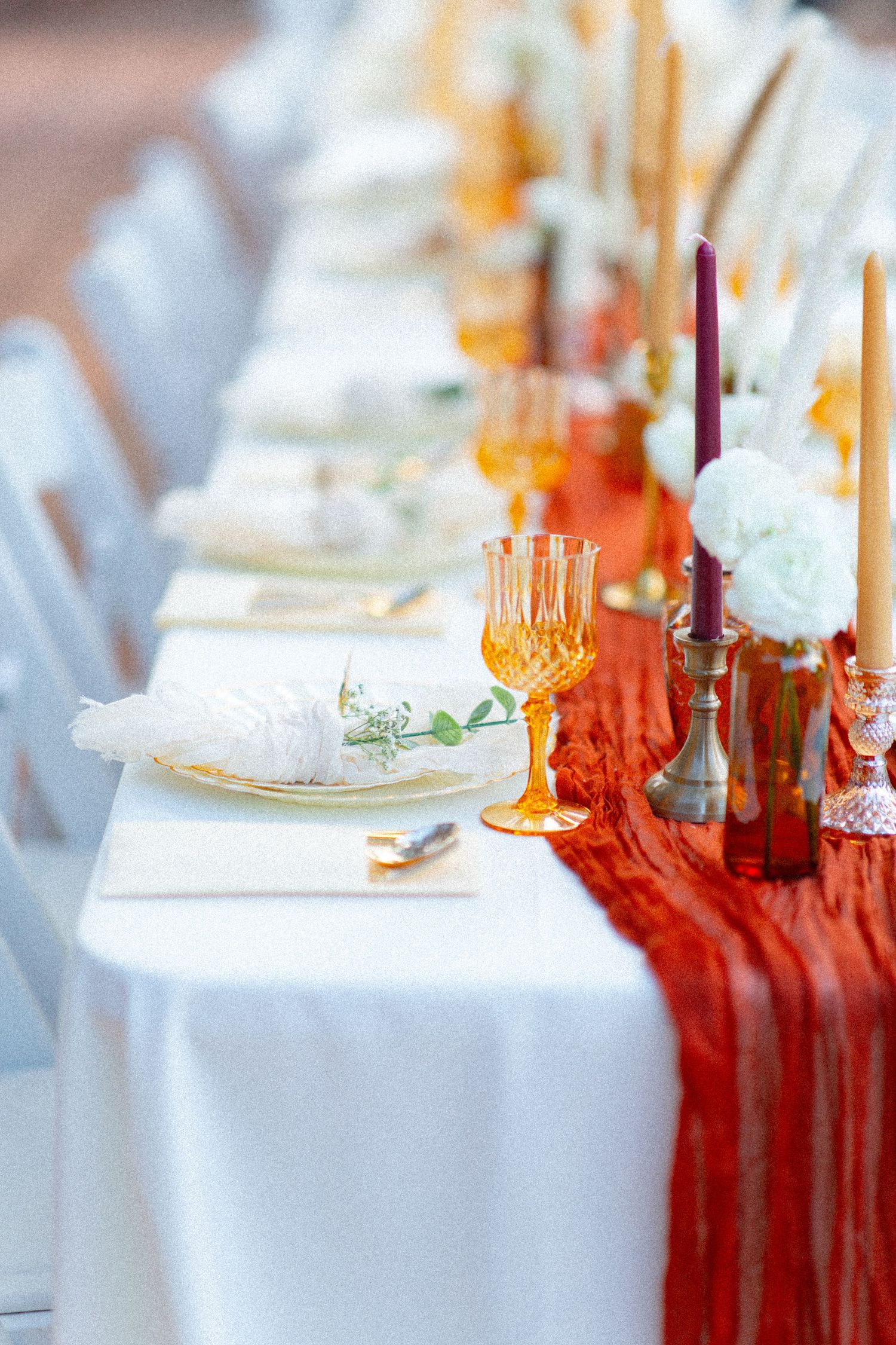 Elegant wedding reception table settings with white linens and orange accents.