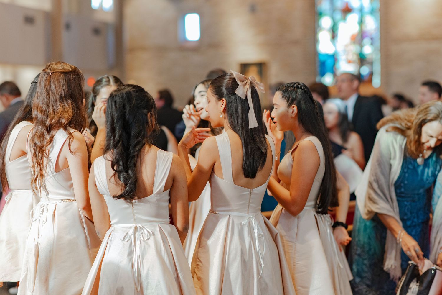 Group photo showing multiple formal white dresses in an elegant indoor venue.