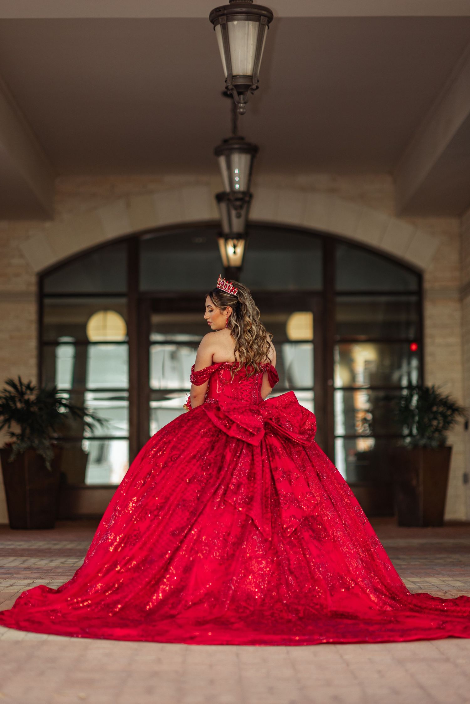 Dramatic red ballgown with full skirt photographed in an elegant covered walkway.