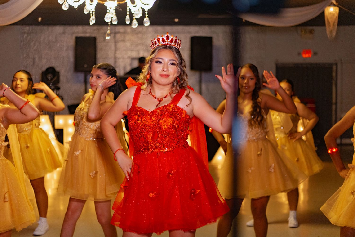 Performers in contrasting red and yellow dresses dance during a celebration.