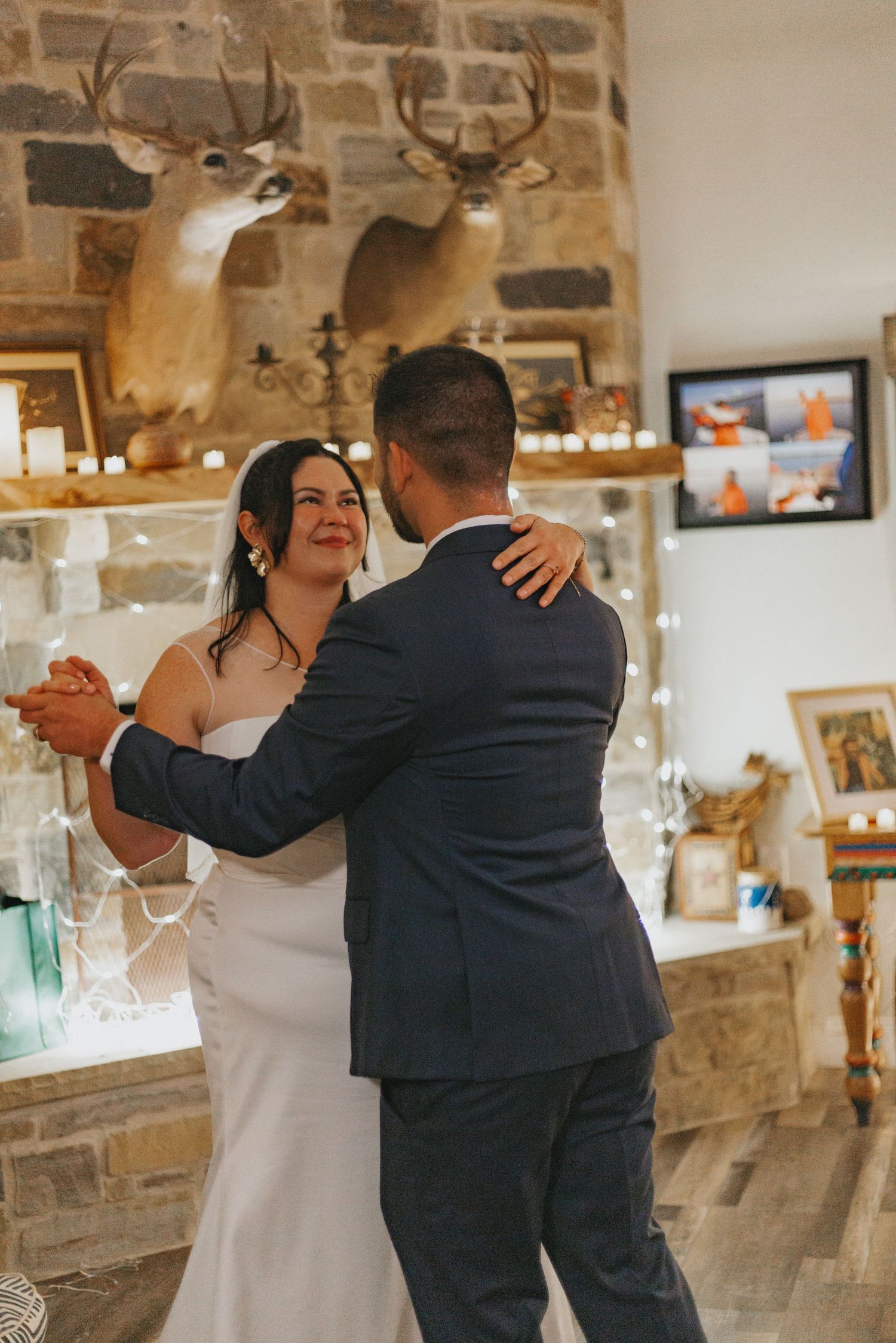 Wedding couple dances romantically in a rustic venue with stone walls and ambient lighting.
