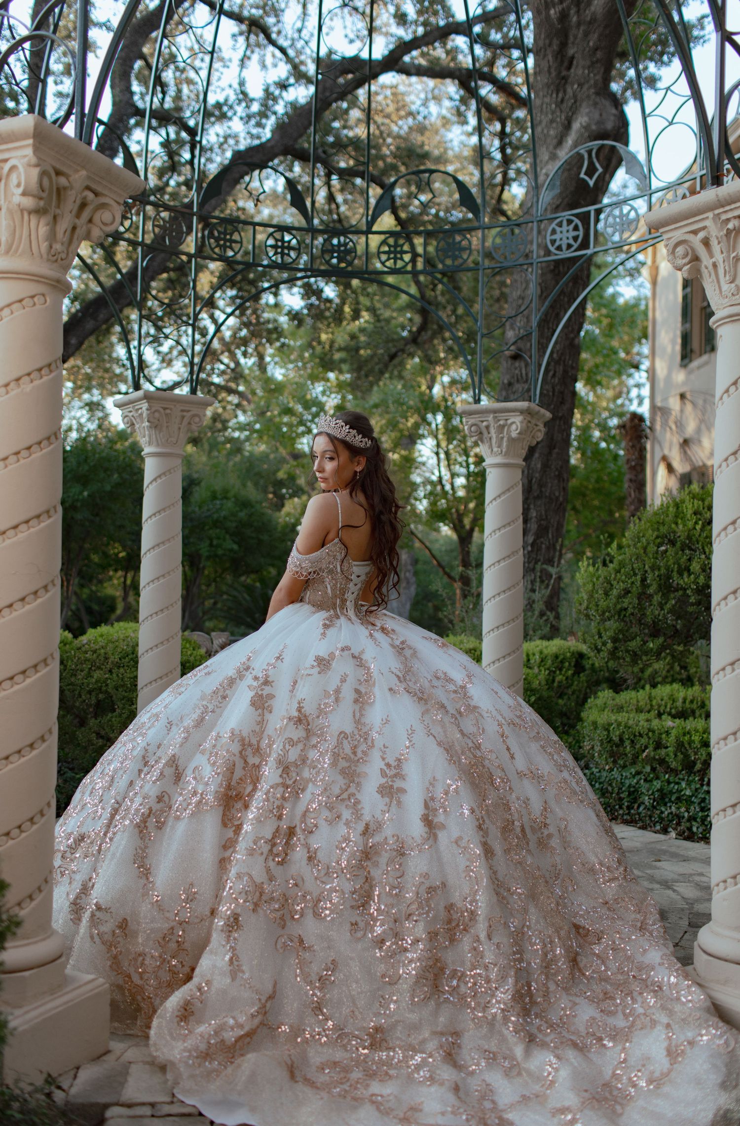 Majestic ball gown with intricate beadwork photographed in an elegant outdoor colonnade.