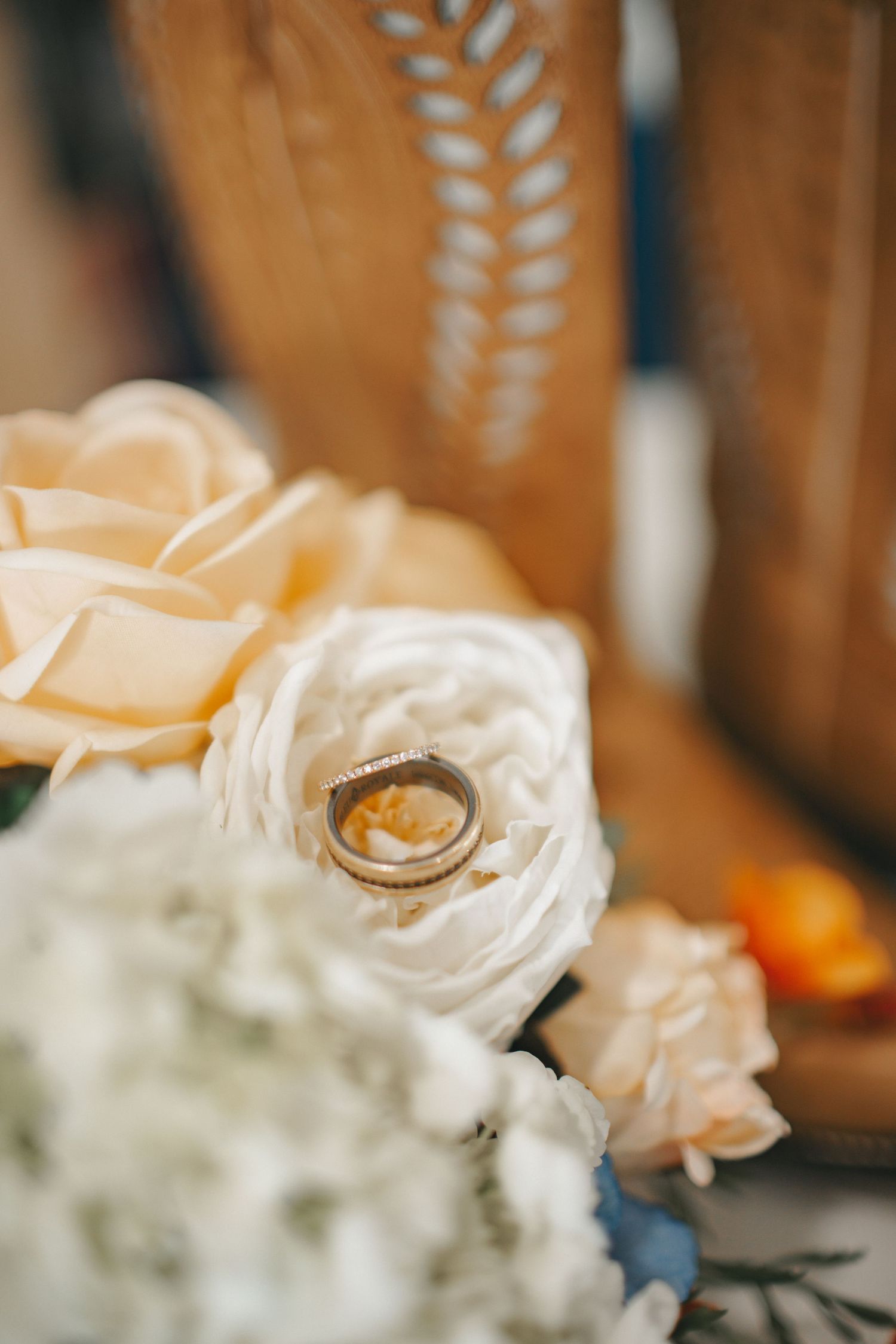 Close-up of white roses with wedding rings nestled among the petals.