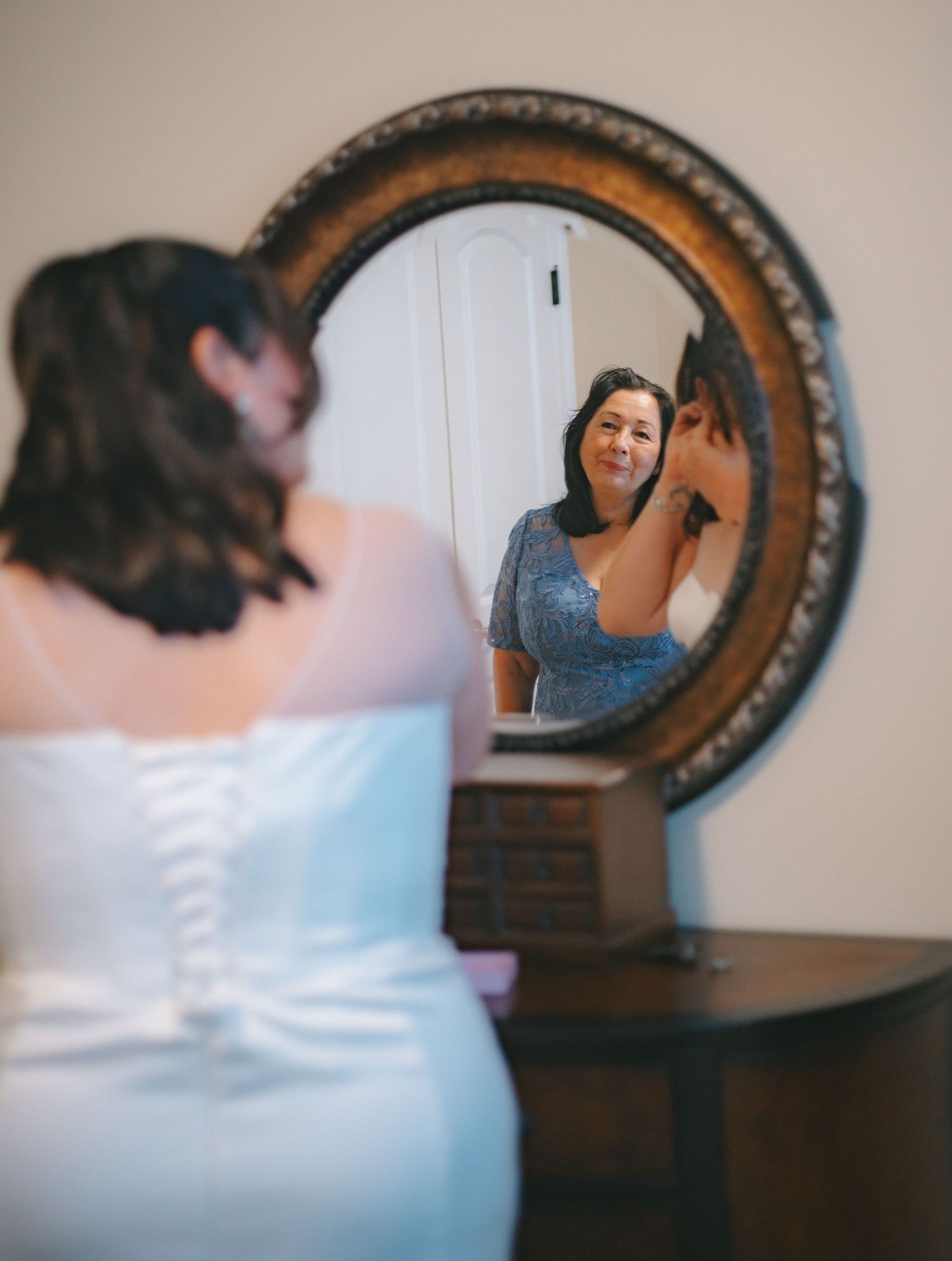 Wedding preparation scene reflected in a decorative wall mirror.