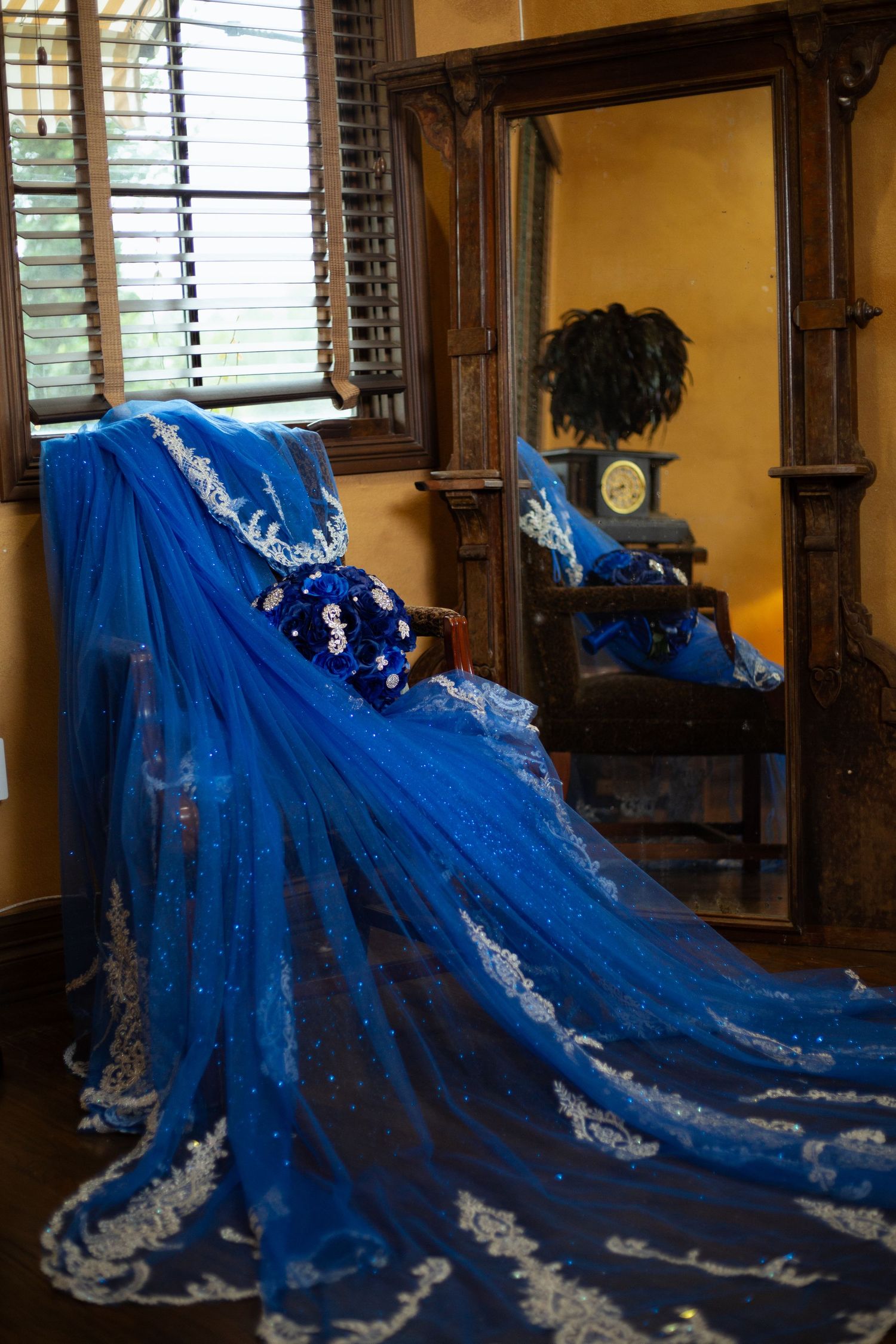 Dramatic royal blue gown with white lace detailing spreads across wooden floor indoors.