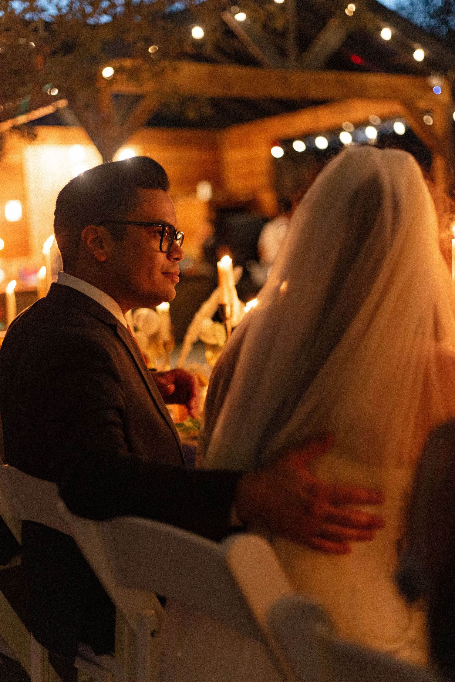 A couple shares an intimate dance moment under twinkling lights at an evening reception.