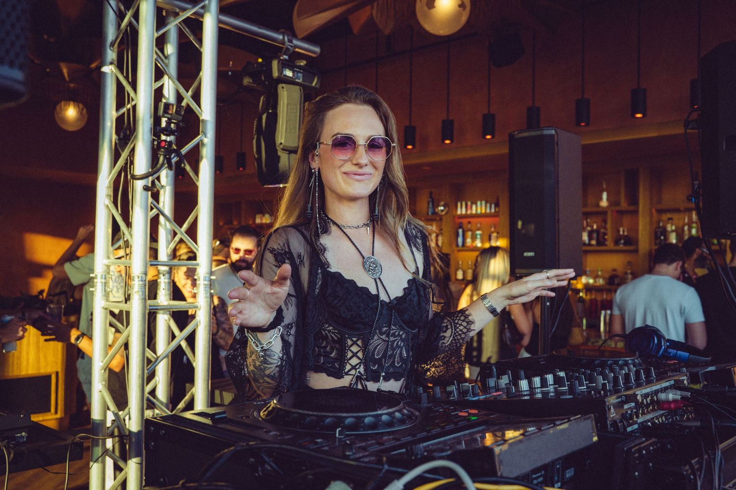 DJ performing at a dimly lit nightclub with professional audio equipment and stage lighting.