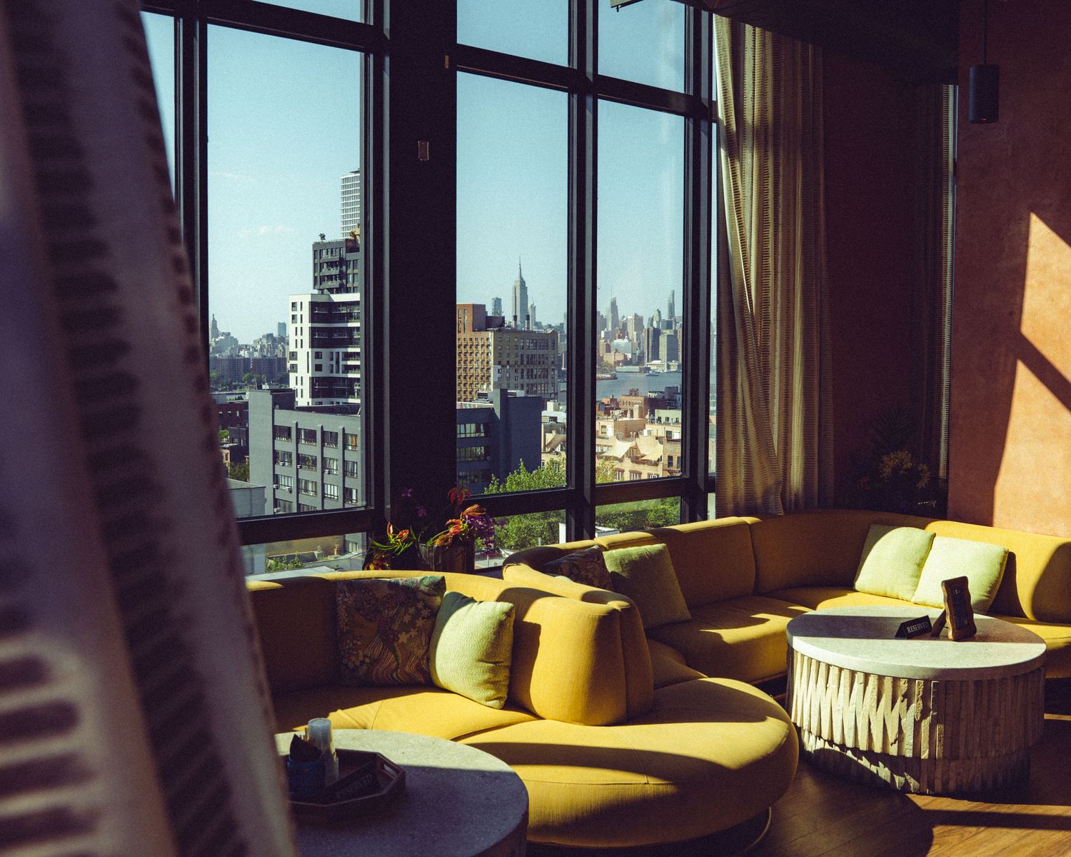 Modern lounge area with city views through large windows and yellow furniture.